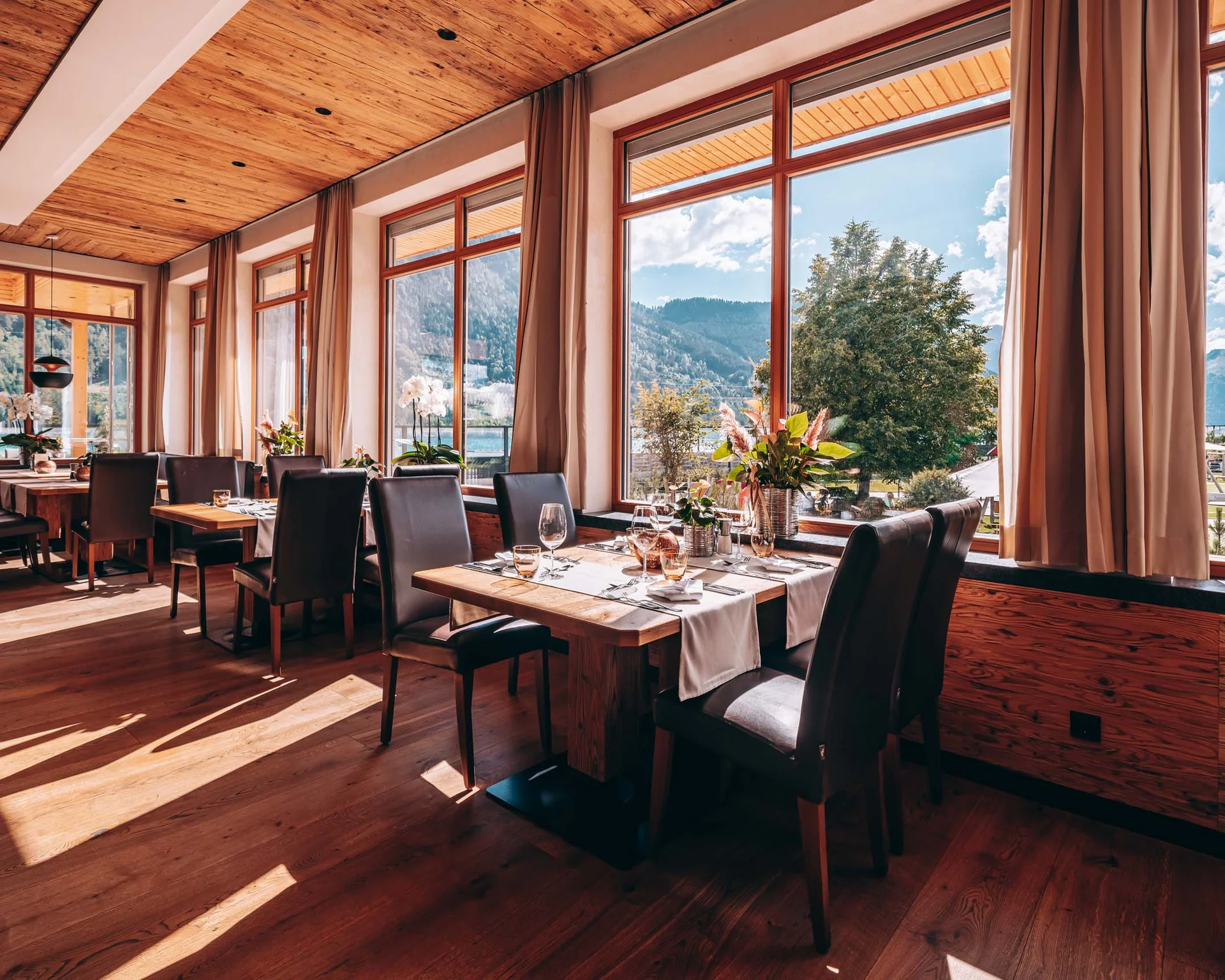 Helles Restaurant mit Holzboden und großen Fenstern mit Bergblick