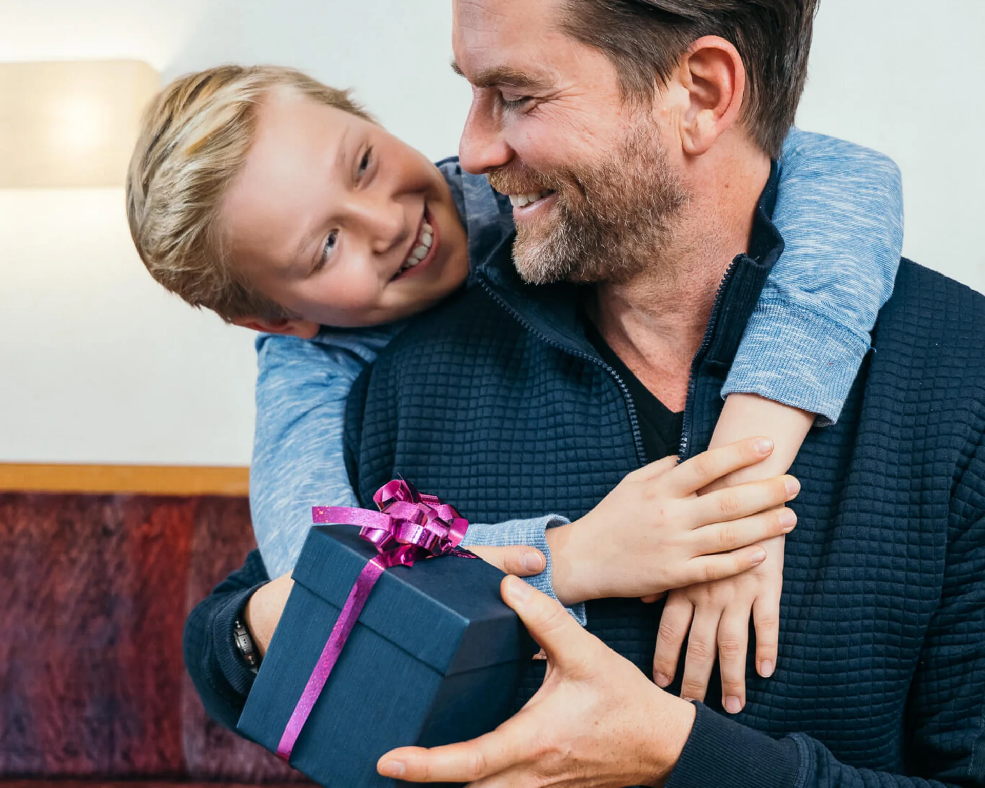 Junge umarmt seinen Vater und gibt ihm ein Geschenk