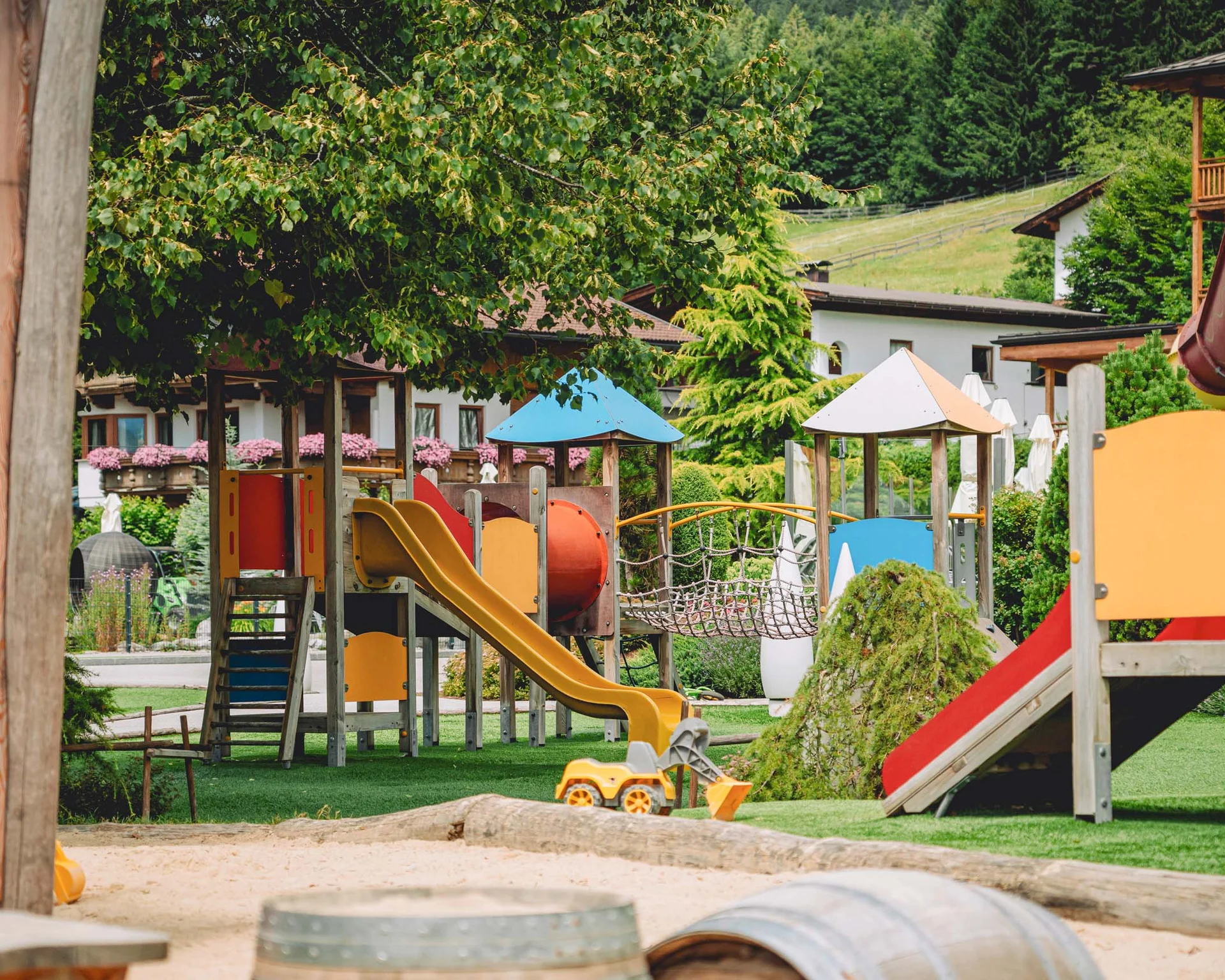 Children's playground with slides, climbing structures, and sandbox in a garden