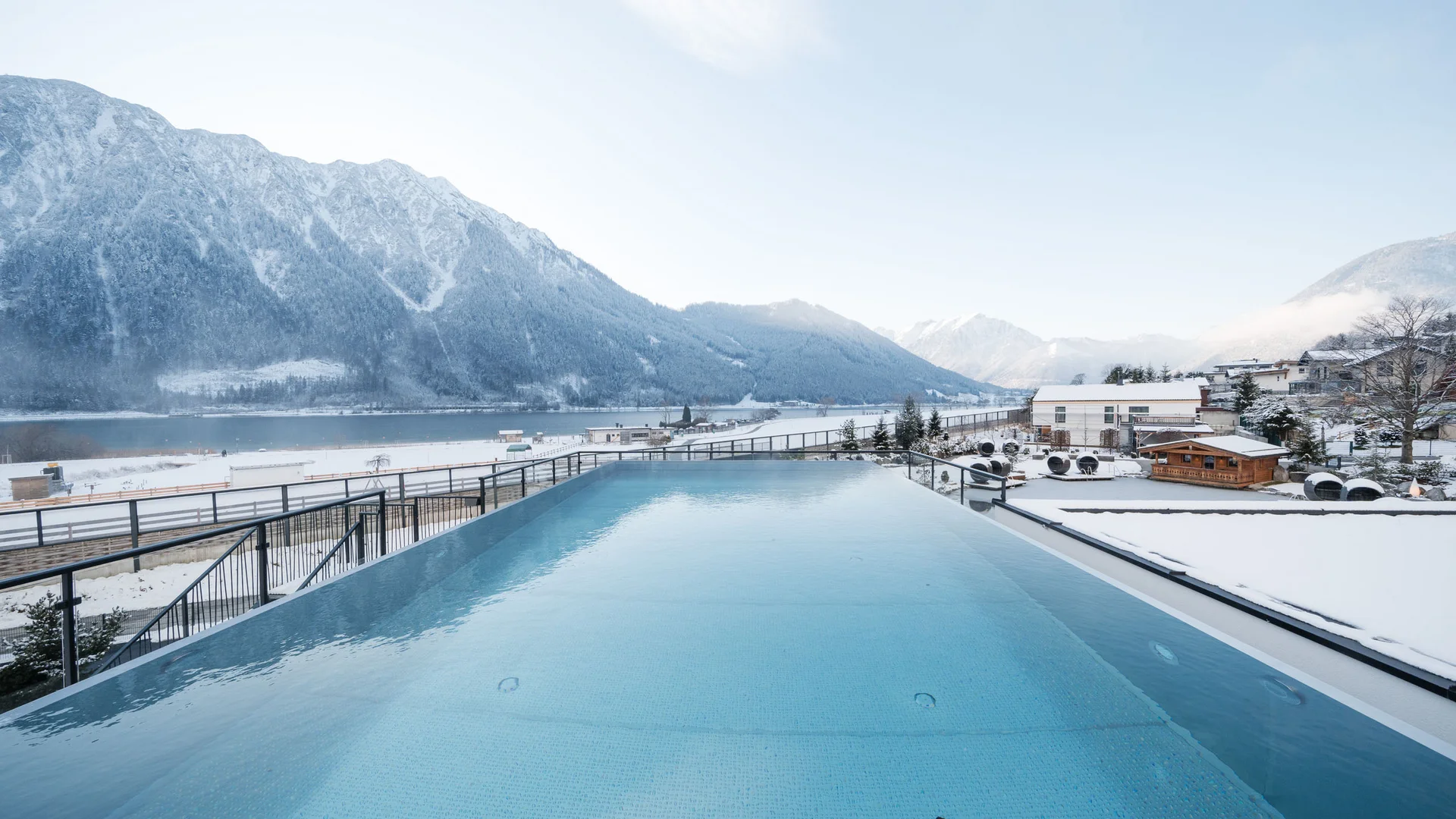 Infinity-Pool mit Blick auf verschneite Berge und Häuser im Winter