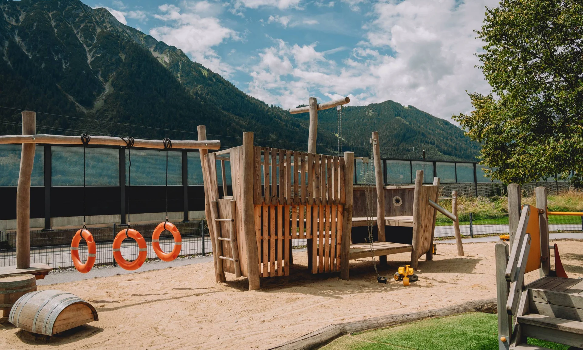 Kinderspielplatz mit Holzgerüst und Bergen im Hintergrund