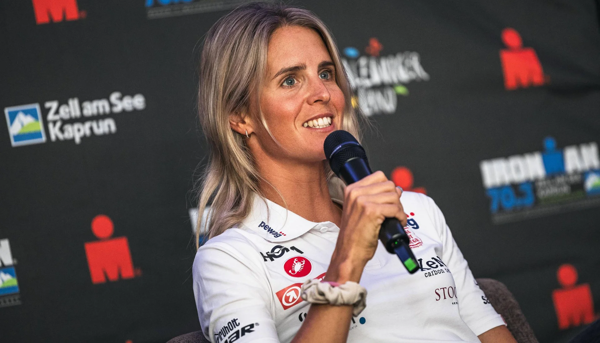 Frau spricht in Mikrofon vor Ironman-Event-Hintergrund