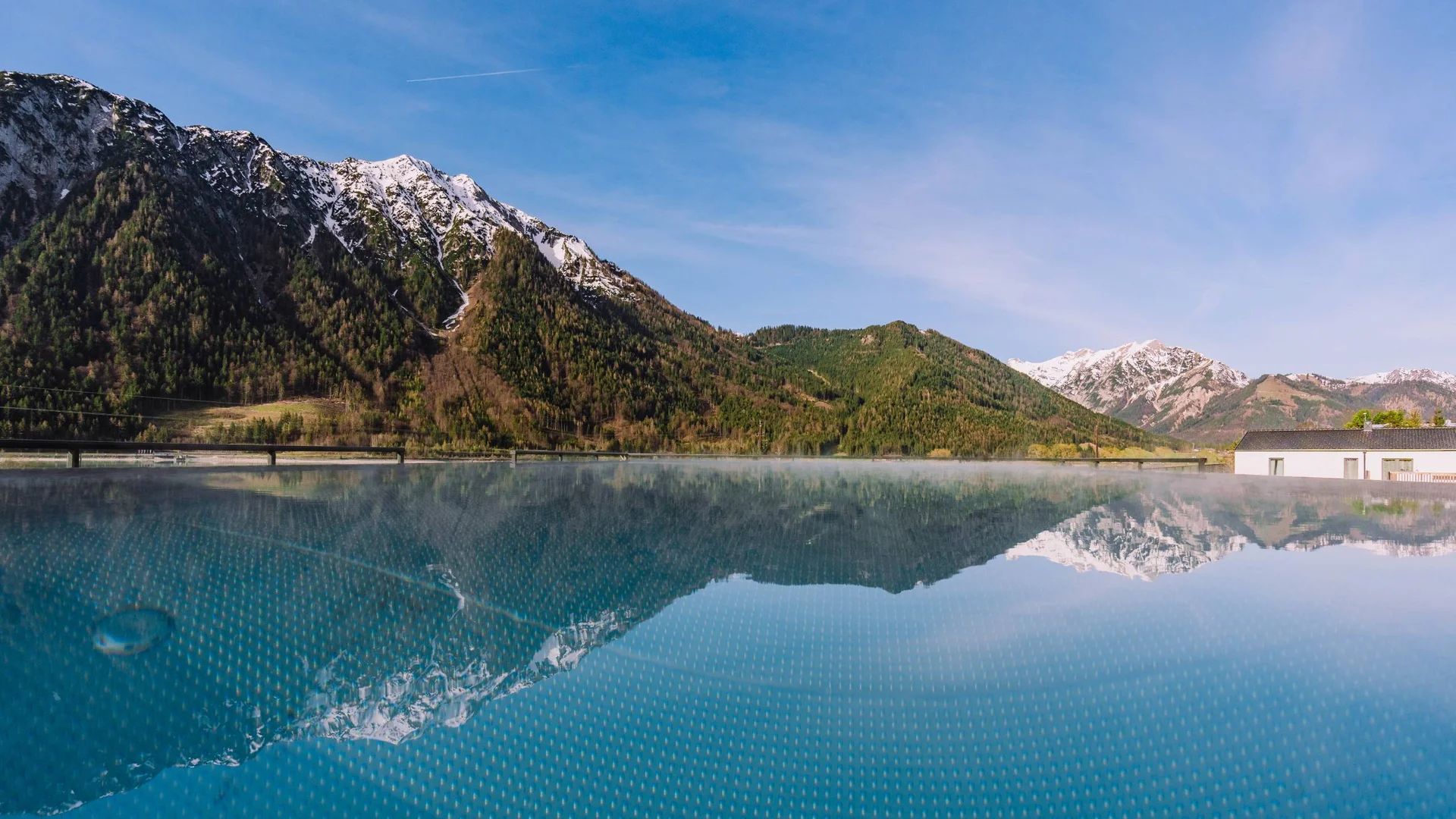 Berglandschaft mit schneebedeckten Gipfeln spiegelt sich in einem ruhigen Pool