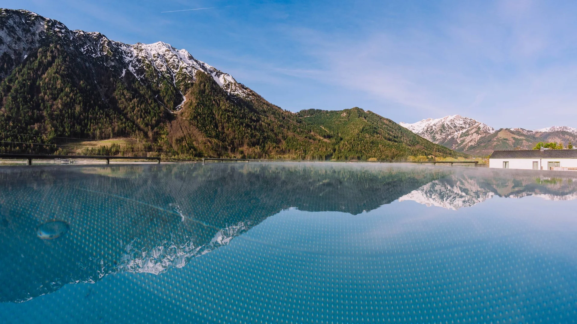 Berglandschaft mit schneebedeckten Gipfeln spiegelt sich in einem ruhigen Pool