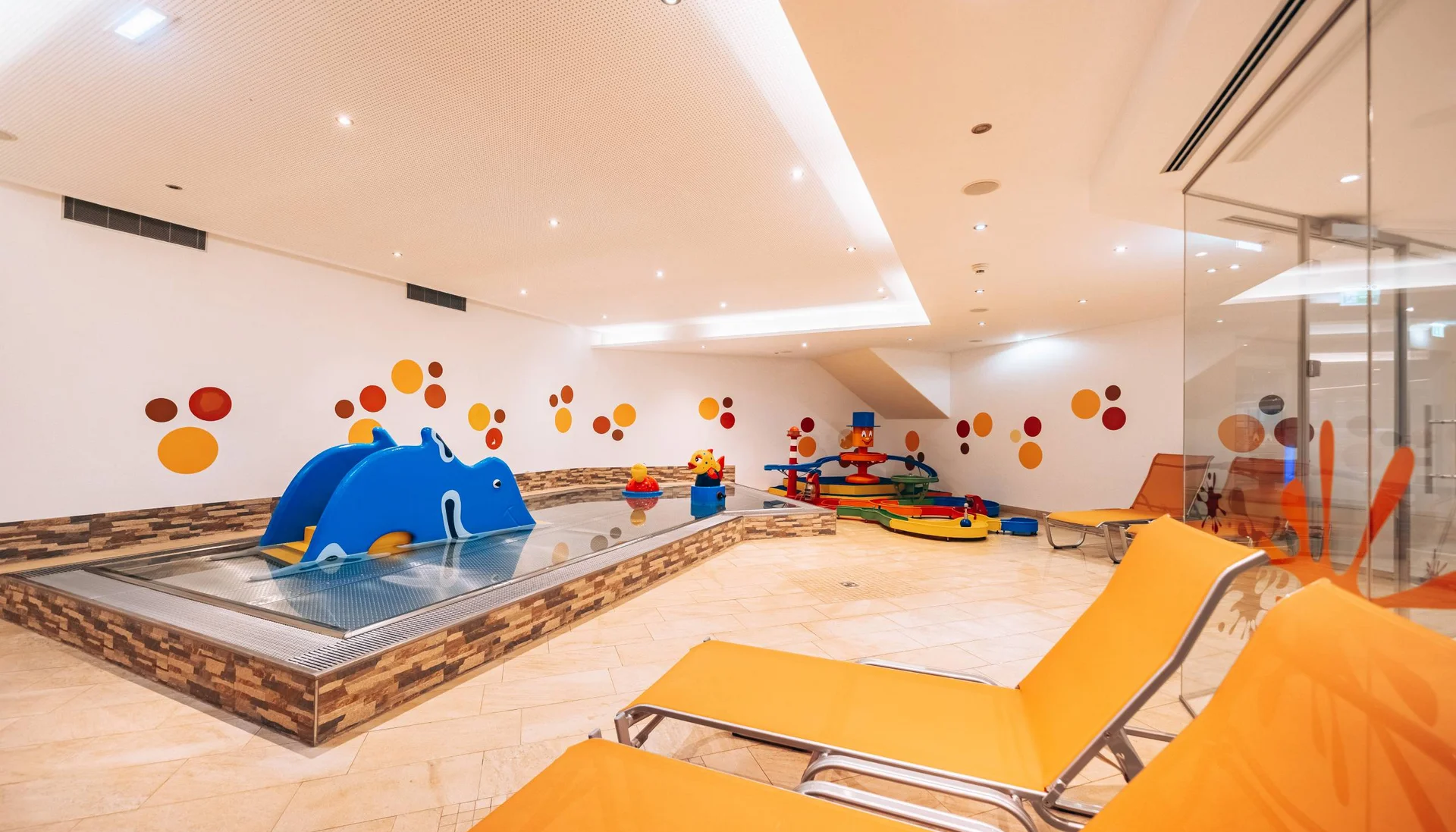 Children's area with colorful small paddling pool and orange lounge chairs