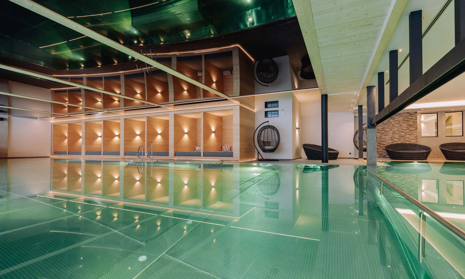 Modernes Hallenbad mit Holzdekor und Sitzbereichen neben dem Pool