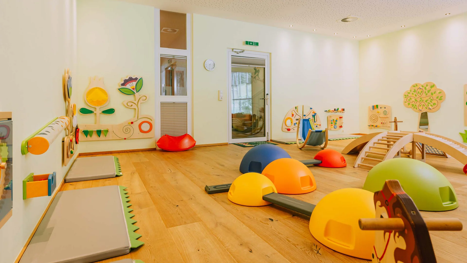 Kinderspielzimmer mit bunten Spielgeräten und Holzspielzeug an der Wand