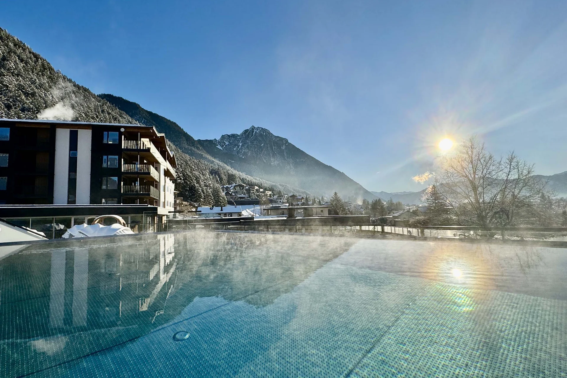 Steaming pool with mountain and sun in the background on a clear winter day