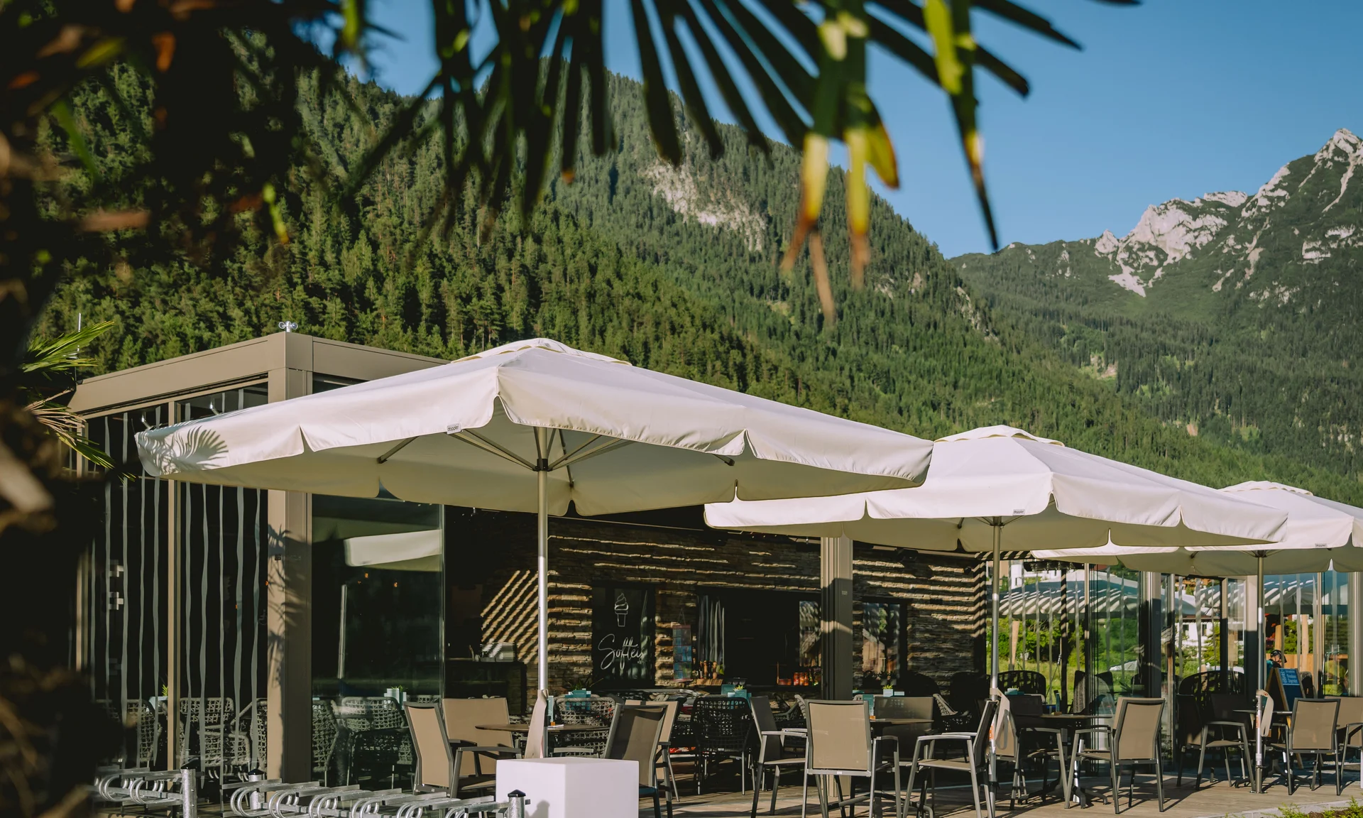 Außenbereich eines Cafés mit Sonnenschirmen und Bergblick