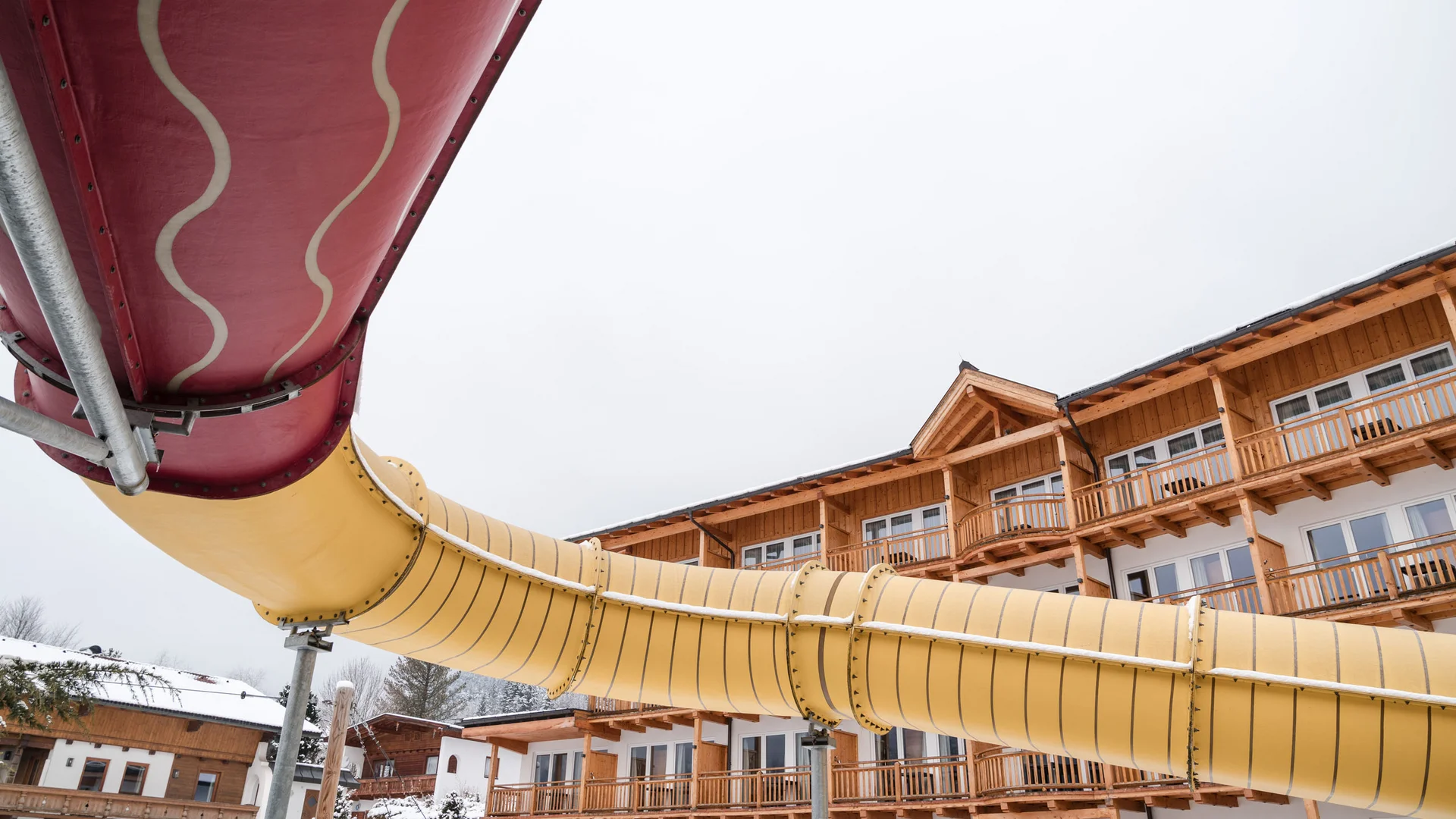Holiday at a family spa hotel in Austria Outdoor slide in front of wooden hotel building in winter