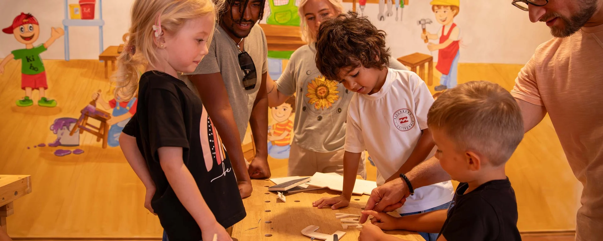 Children and adults working together on a wood project in a workshop