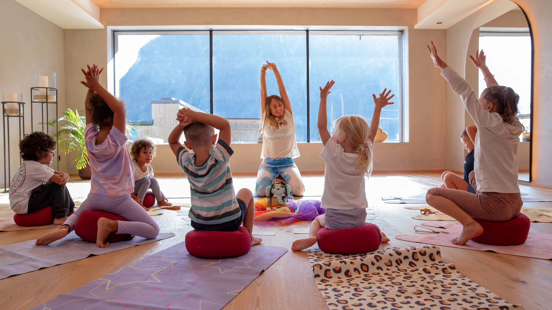 Children practicing yoga in a bright room with mountain view