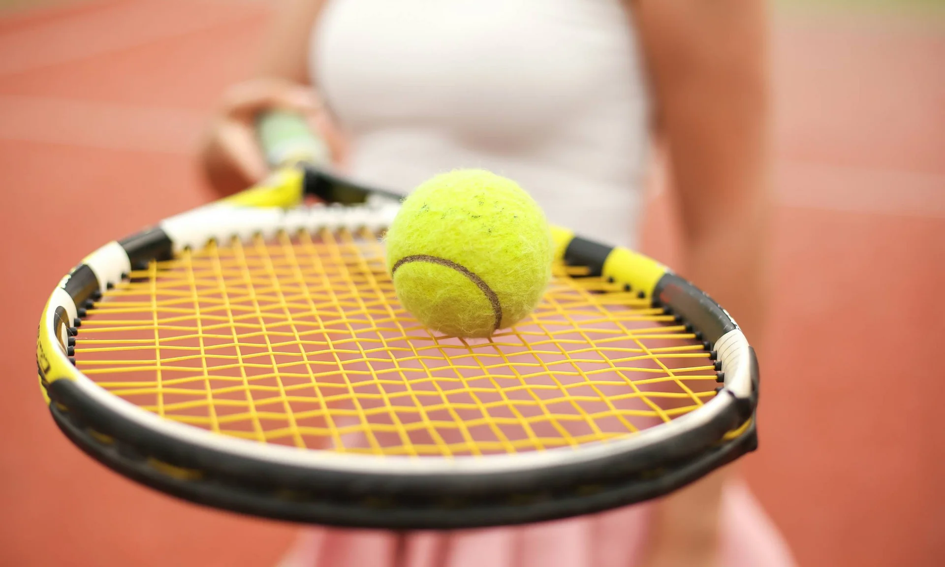 Tennisball auf Tennisschläger auf rotem Tennisplatz