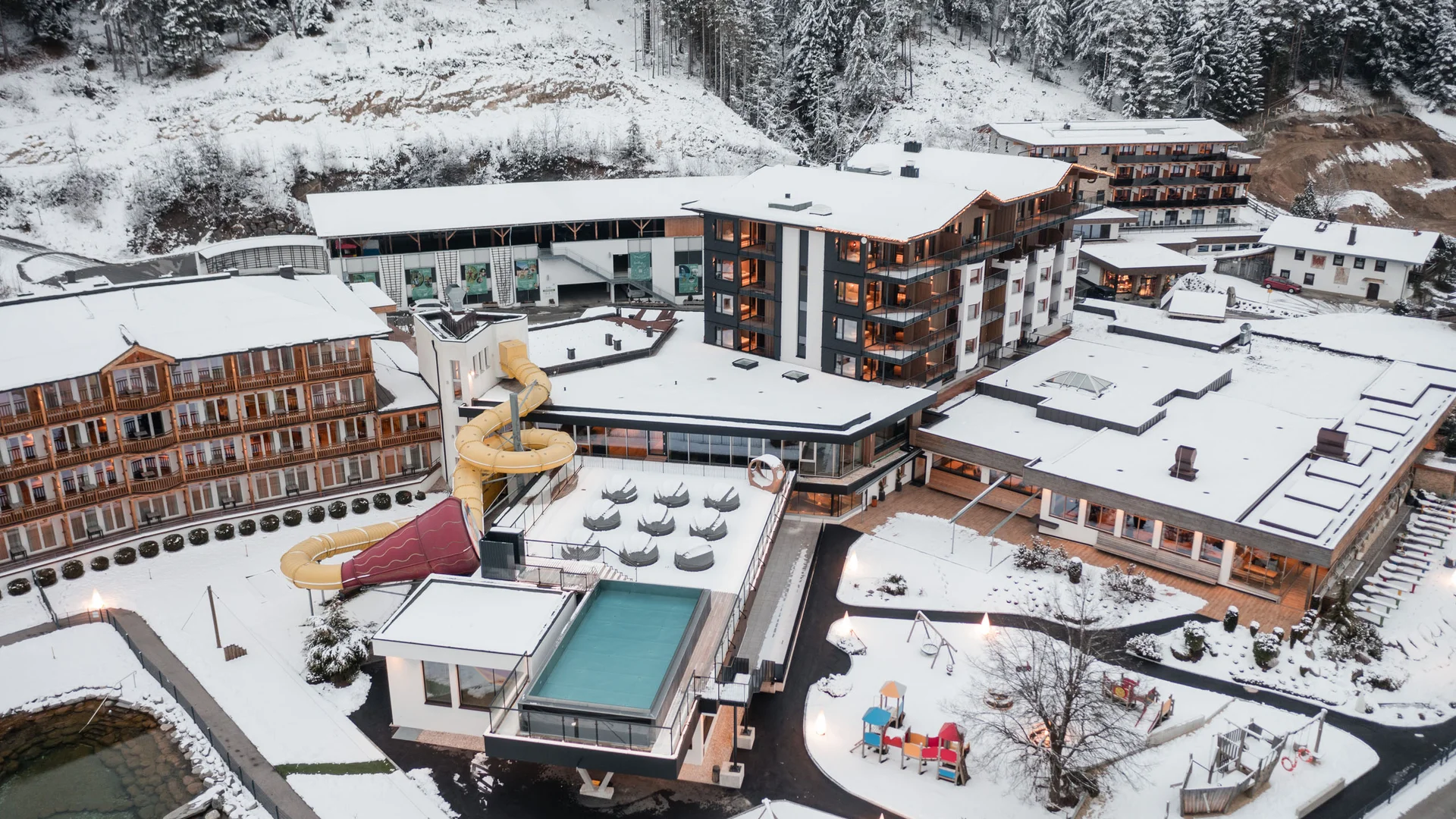 Holiday at a family spa hotel in Austria Aerial view of a snow-covered hotel with a water slide in winter