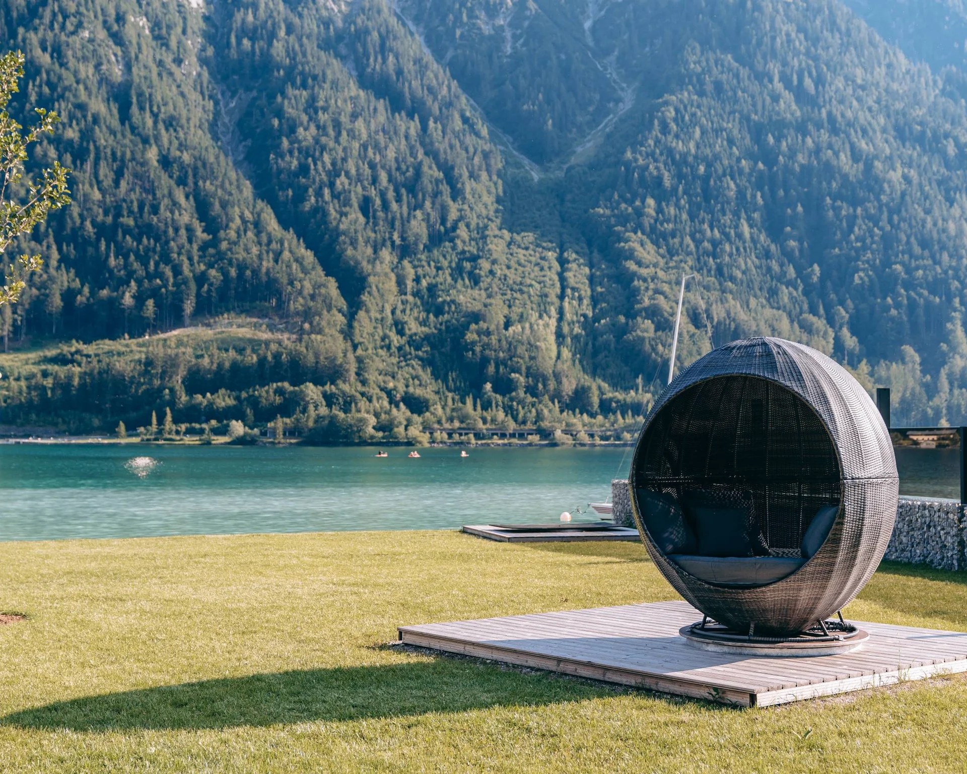 Rundes Loungesessel auf einer Wiese mit Berg- und Seeblick im Hintergrund