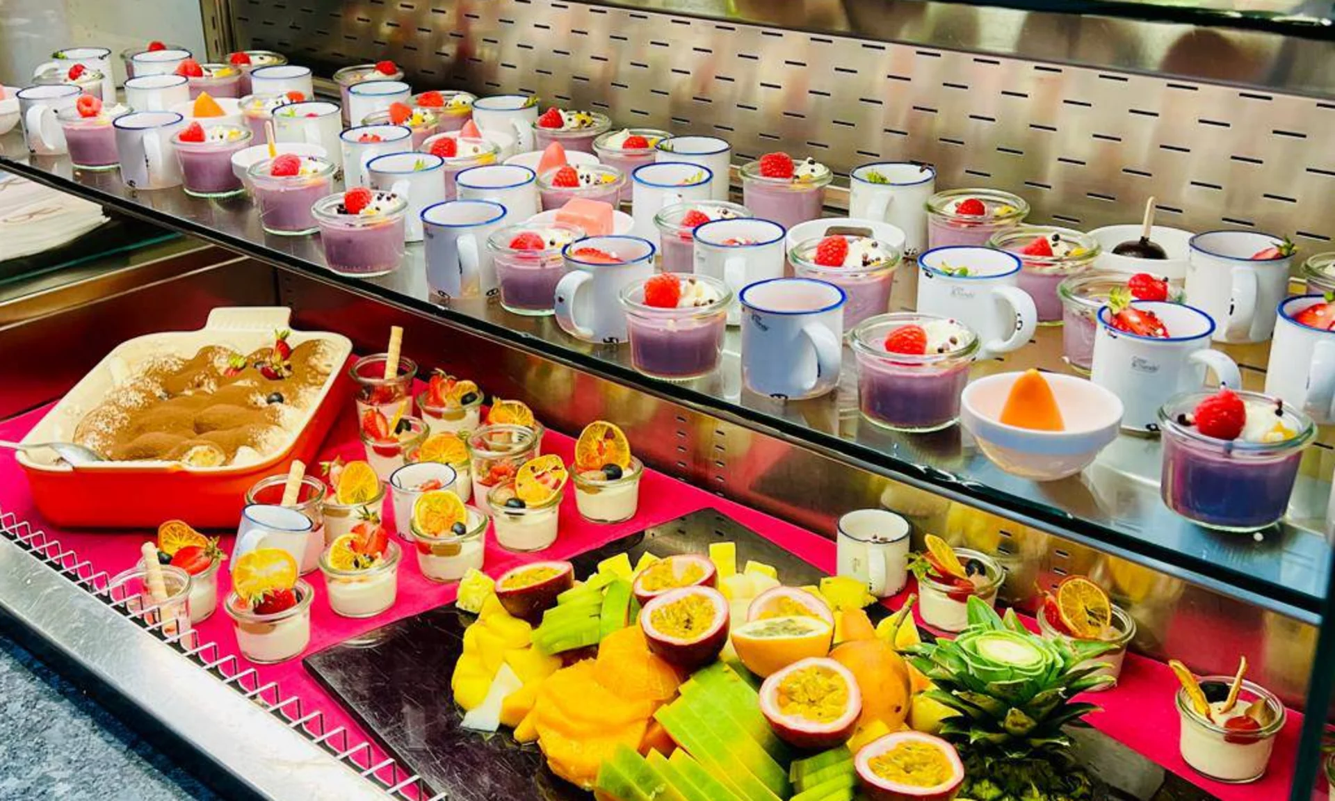 Buffet with various desserts and fresh fruit in glasses and cups