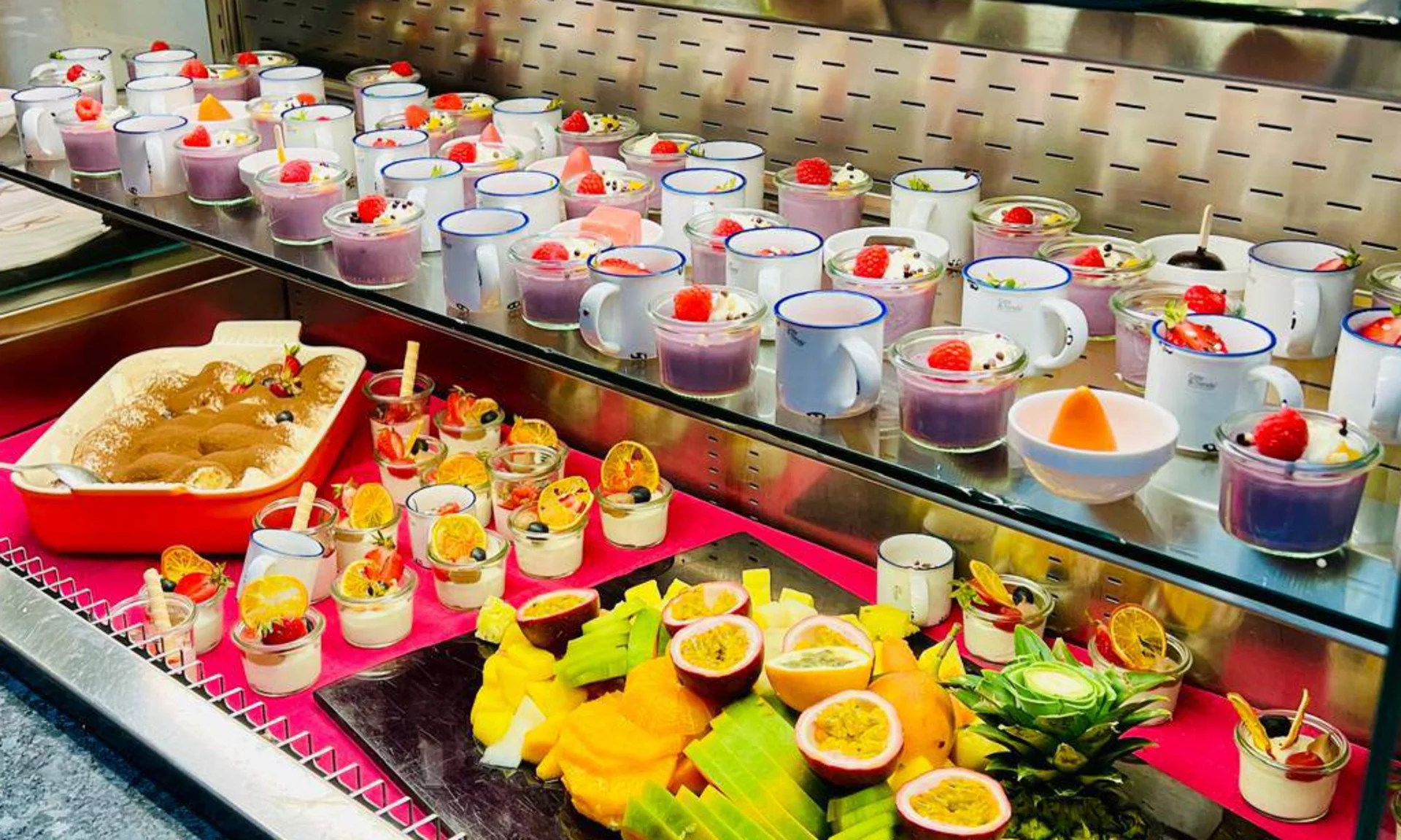 Buffet mit vielfältigen Desserts und frischem Obst in Gläsern und Tassen