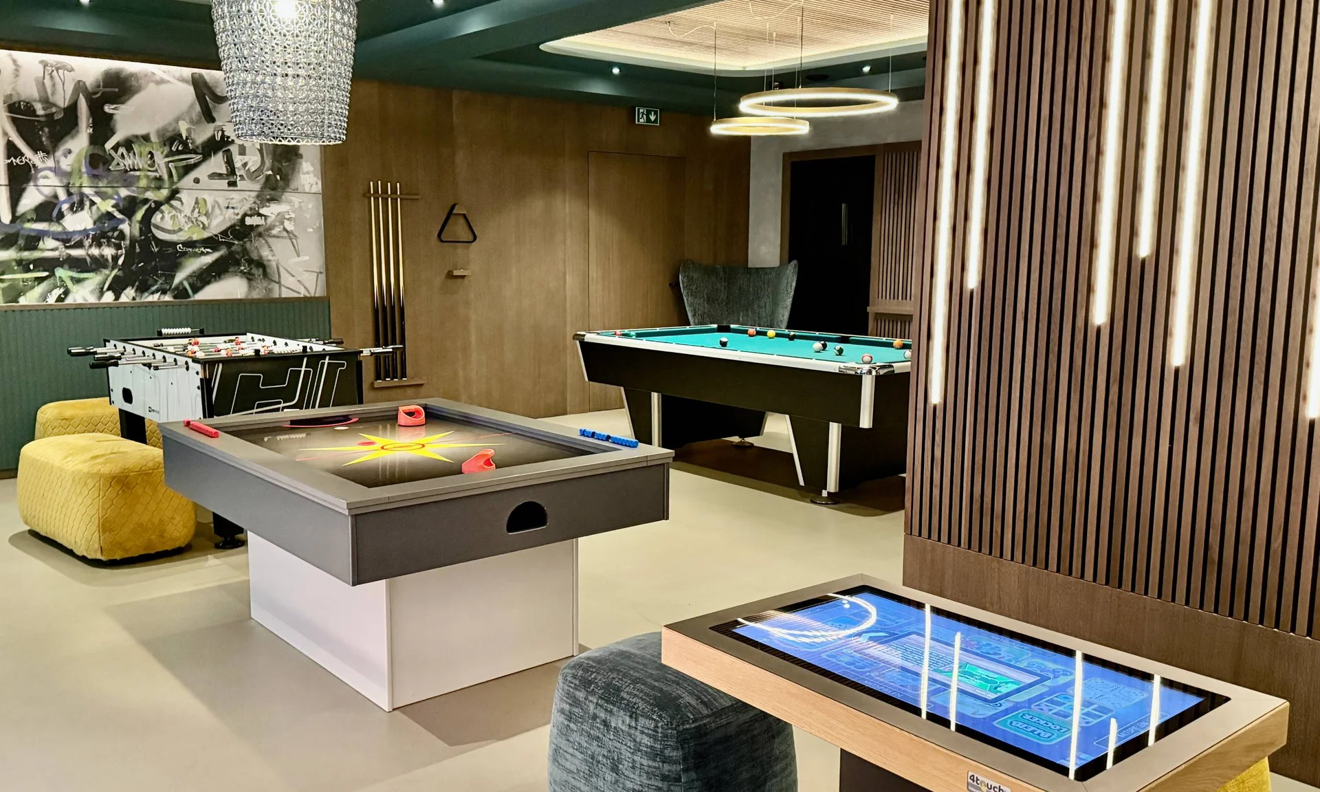 Moderner Spieleraum mit Airhockey-, Kicker- und Billardtisch sowie digitalem Spieltisch