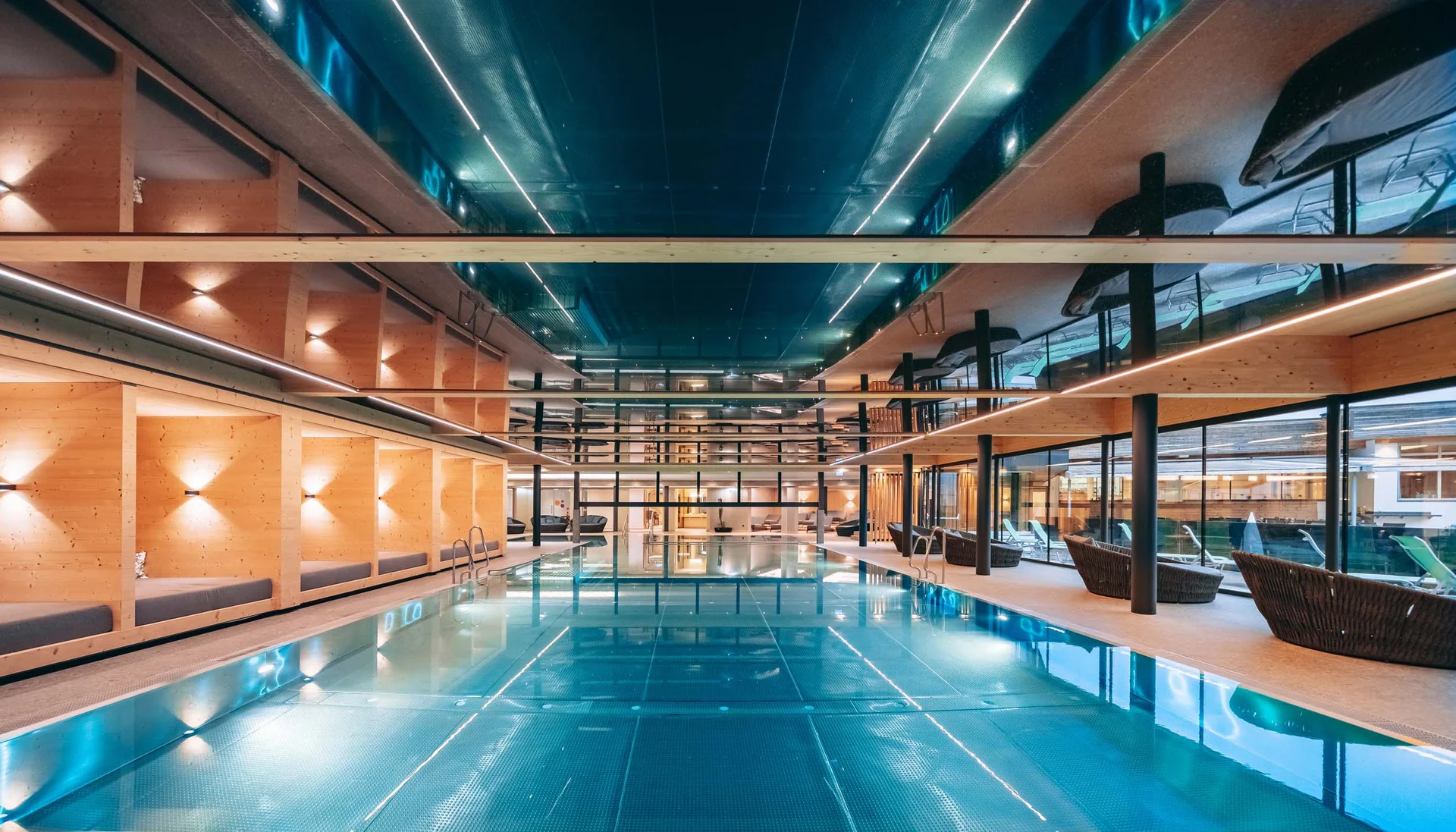 Innenaufnahme eines modernen Schwimmbads mit Holzverkleidung und Lounge-Bereichen