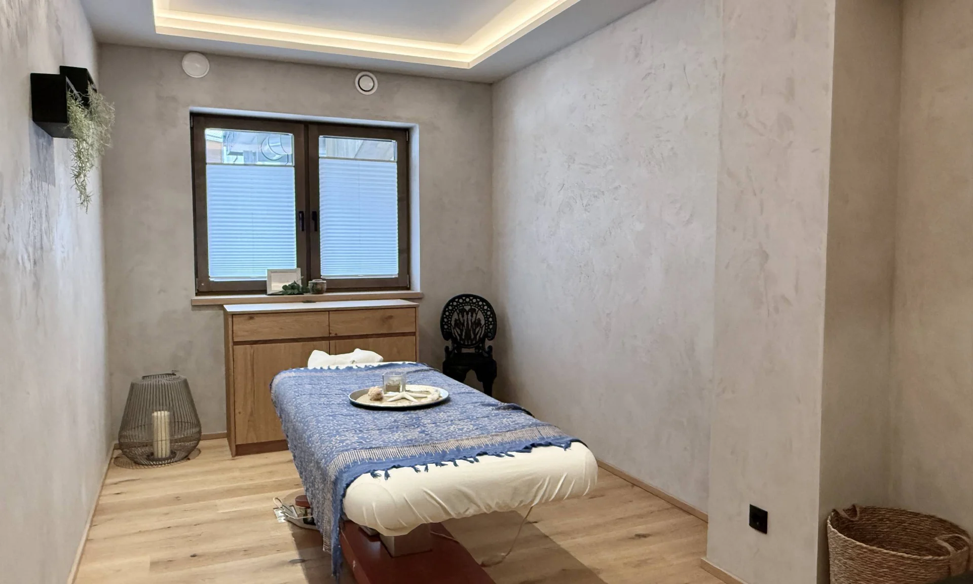 Calm massage room with treatment bed, wooden furniture, and relaxing decor
