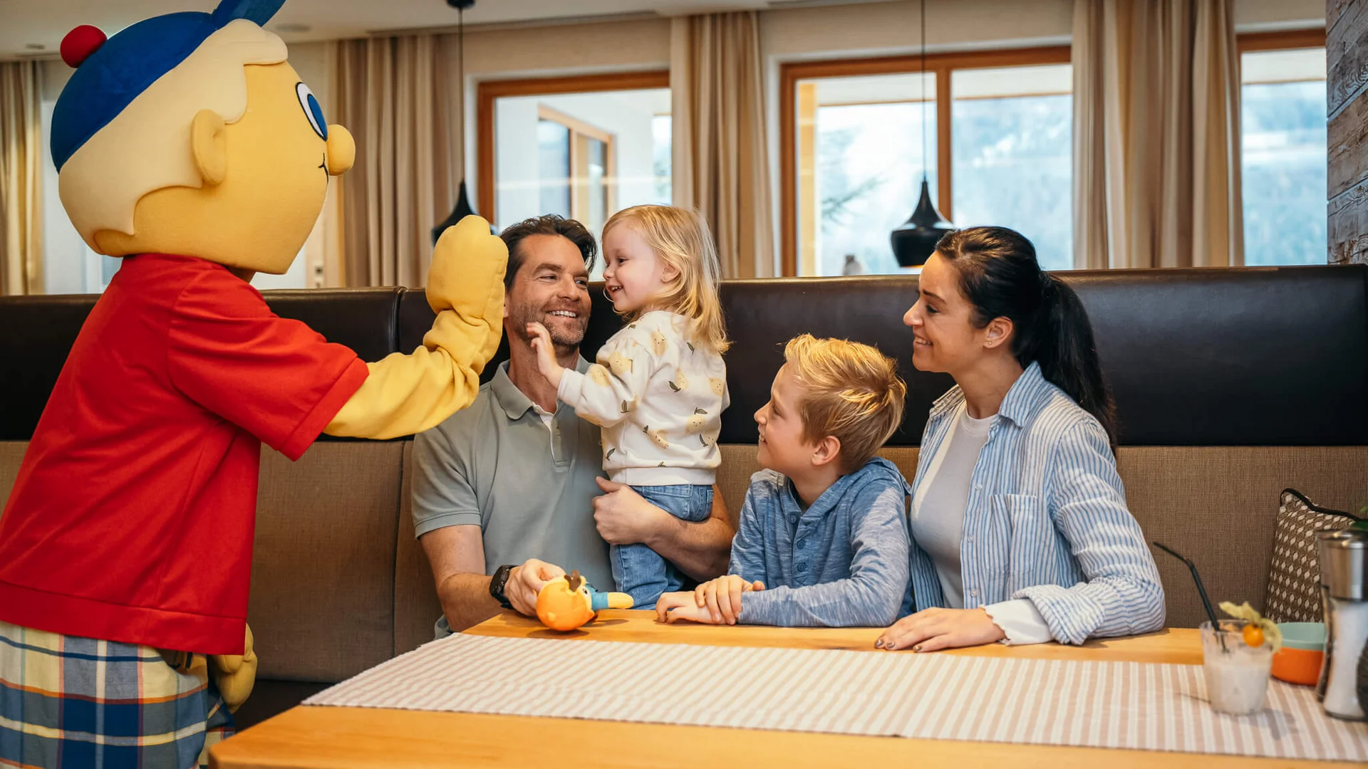 Familie mit zwei Kindern trifft eine Person in einer bunten Cartoon-Figur Kostüm