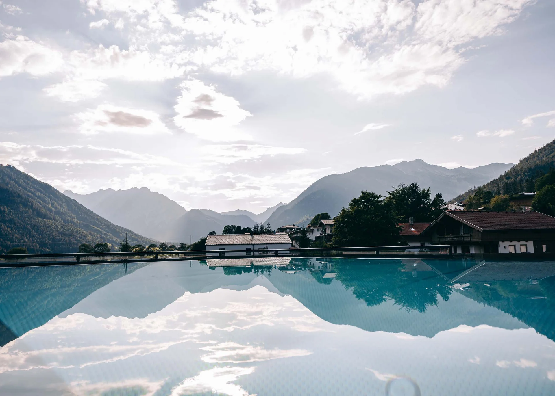Mountain landscape with houses and water pool reflecting sky and mountains