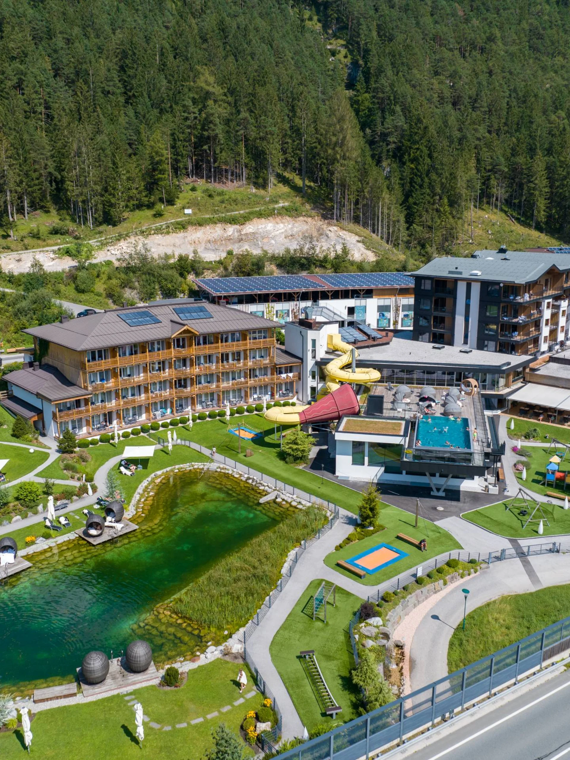 Luftaufnahme eines Resorts mit Teich, Pool und Wald im Hintergrund
