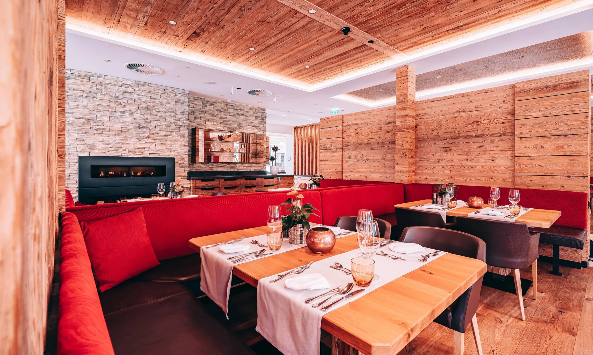 Modernes Restaurant mit roten Sitzbänken, Holztischen und Kamin