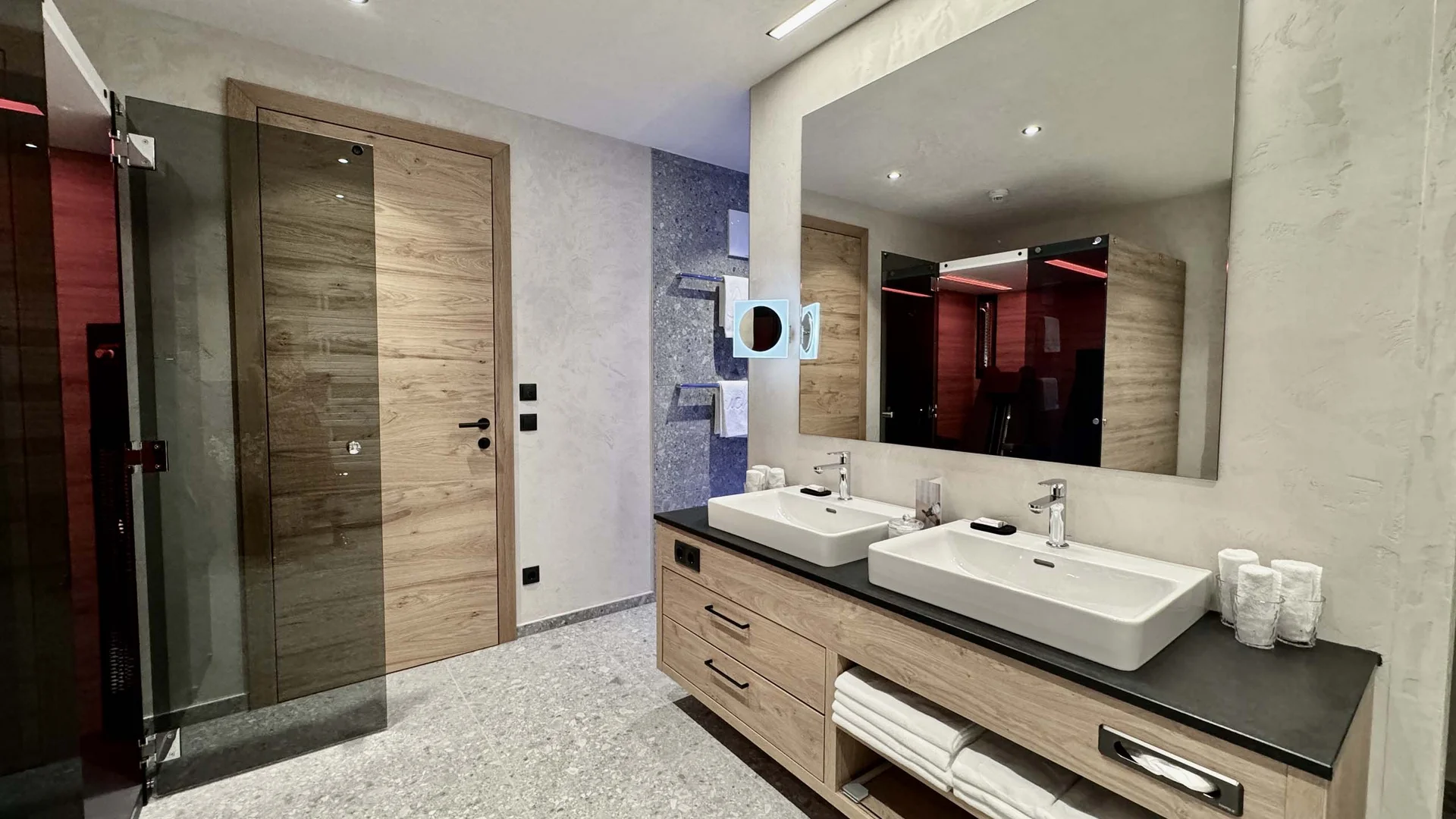 Moderne Badezimmer mit Holz- und Steindetails, Doppelwaschbecken und großen Spiegel