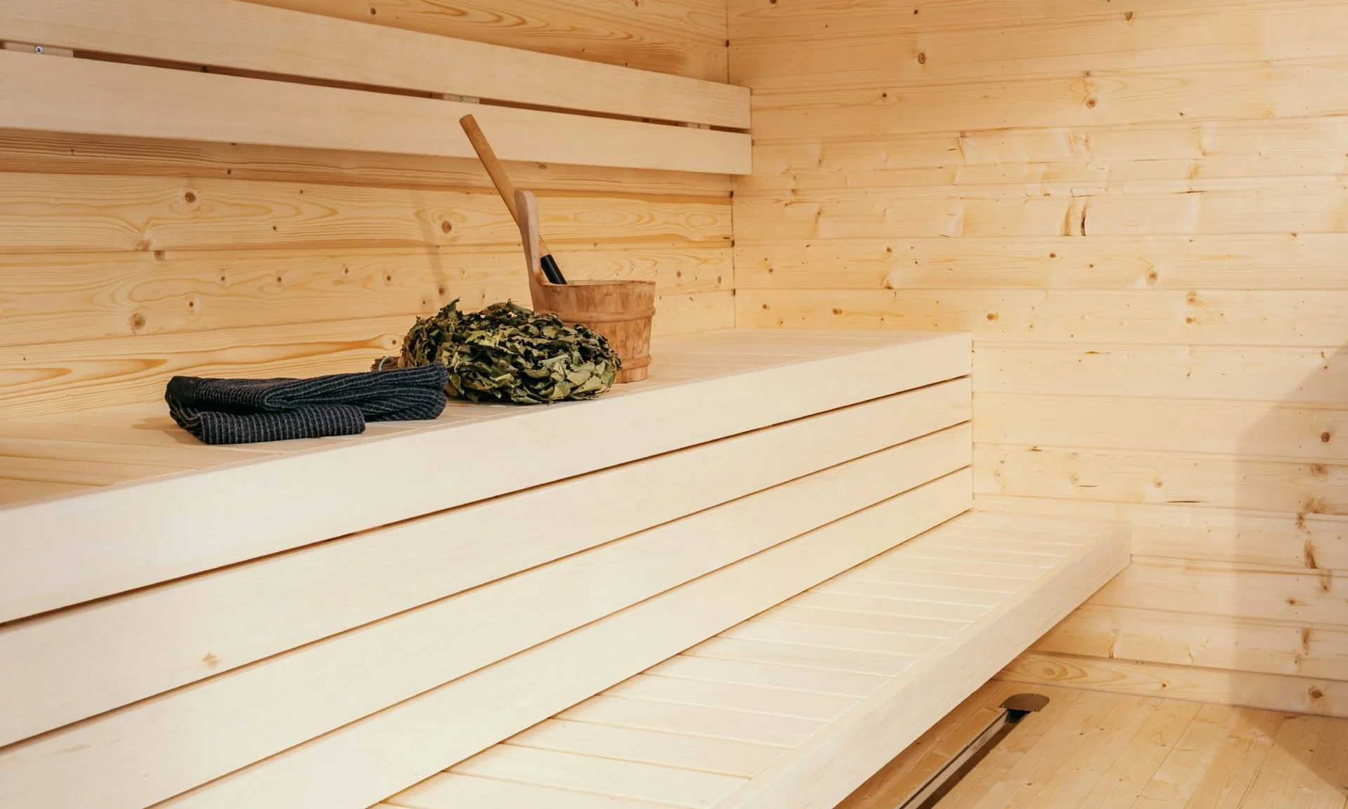 Moderner Saunaraum mit Holzbänken und Saunaofen mit Saunazubehör