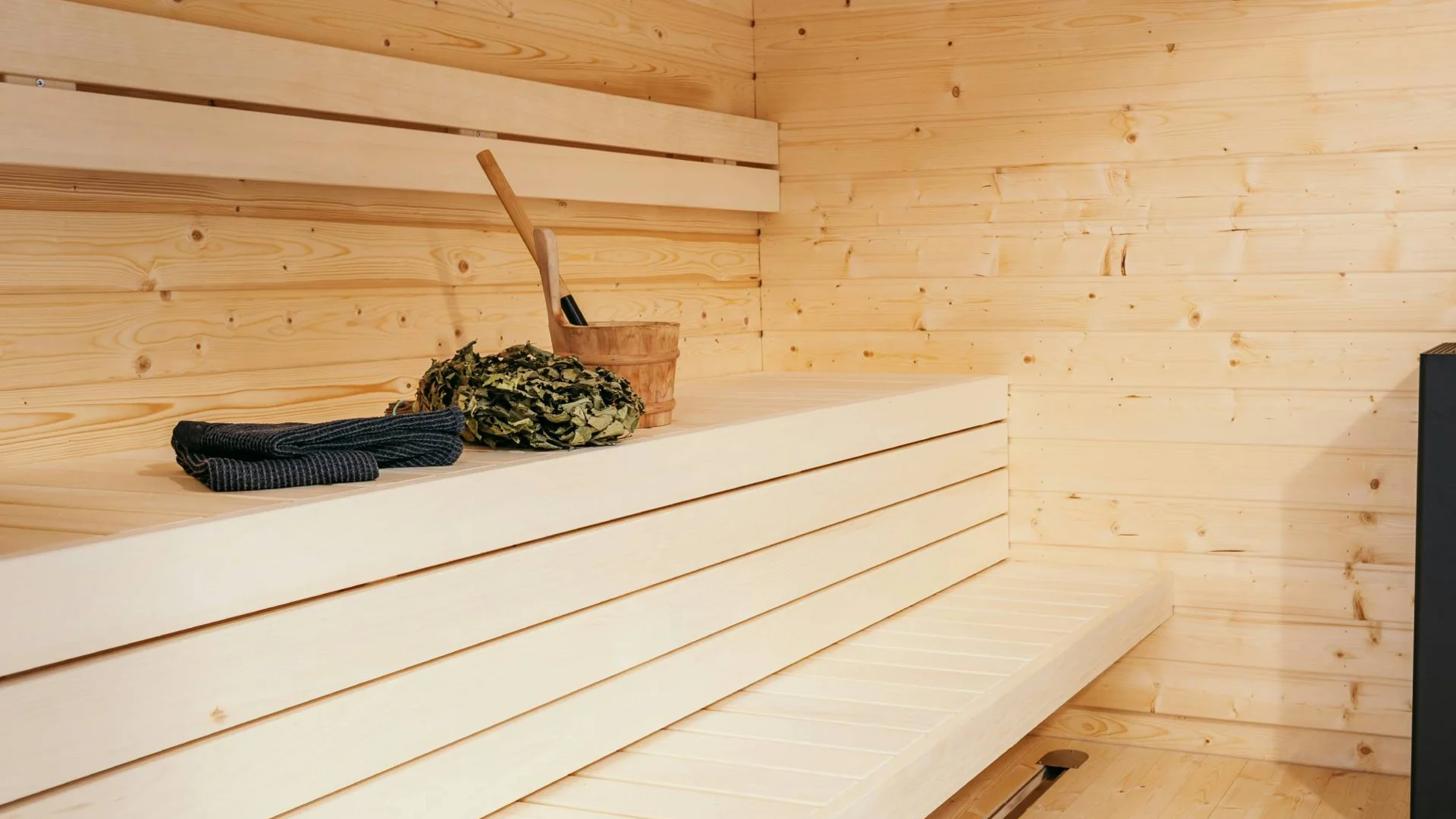 Moderner Saunaraum mit Holzbänken und Saunaofen mit Saunazubehör