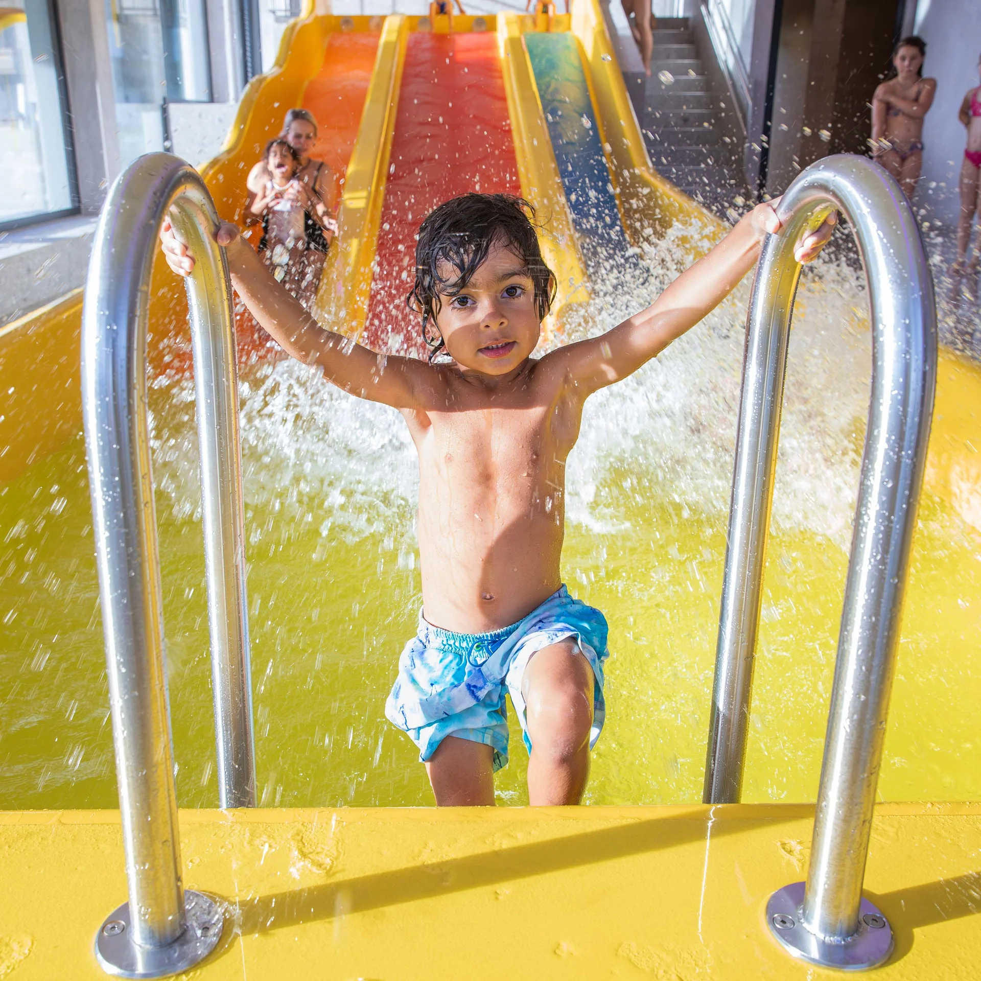 Kind steigt nach Rutsche aus Wasserbecken in einem Hallenbad
