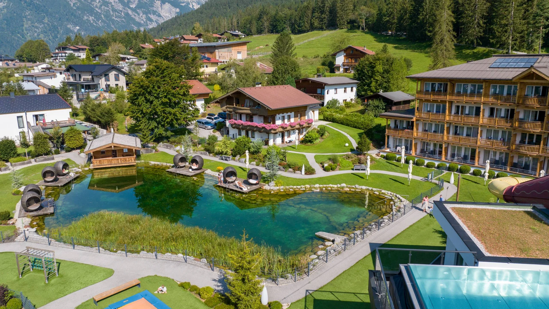 Hotelanlage mit natürlichem Schwimmteich und Liegebereichen in den Bergen