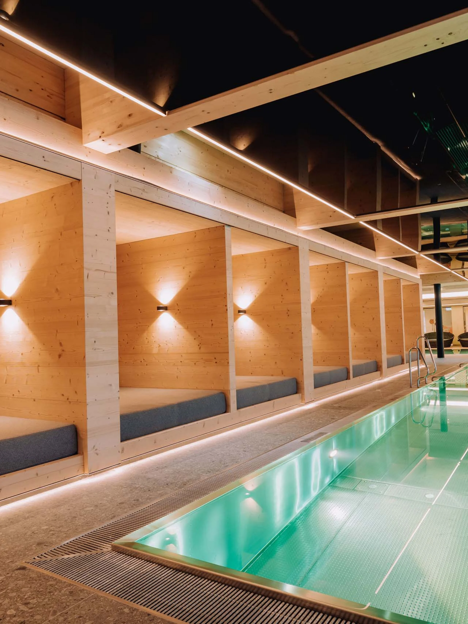 Modernes Hallenbad mit Holzliegen und indirekter Beleuchtung