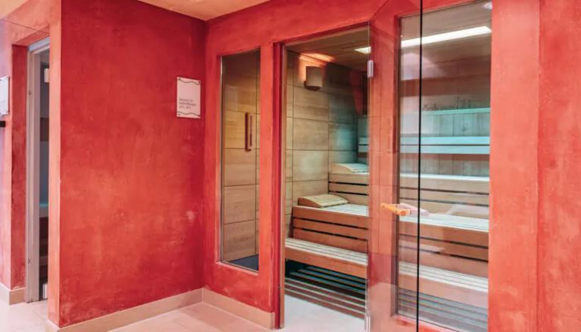 Moderne Sauna mit Glastür in rotem Wellnessbereich