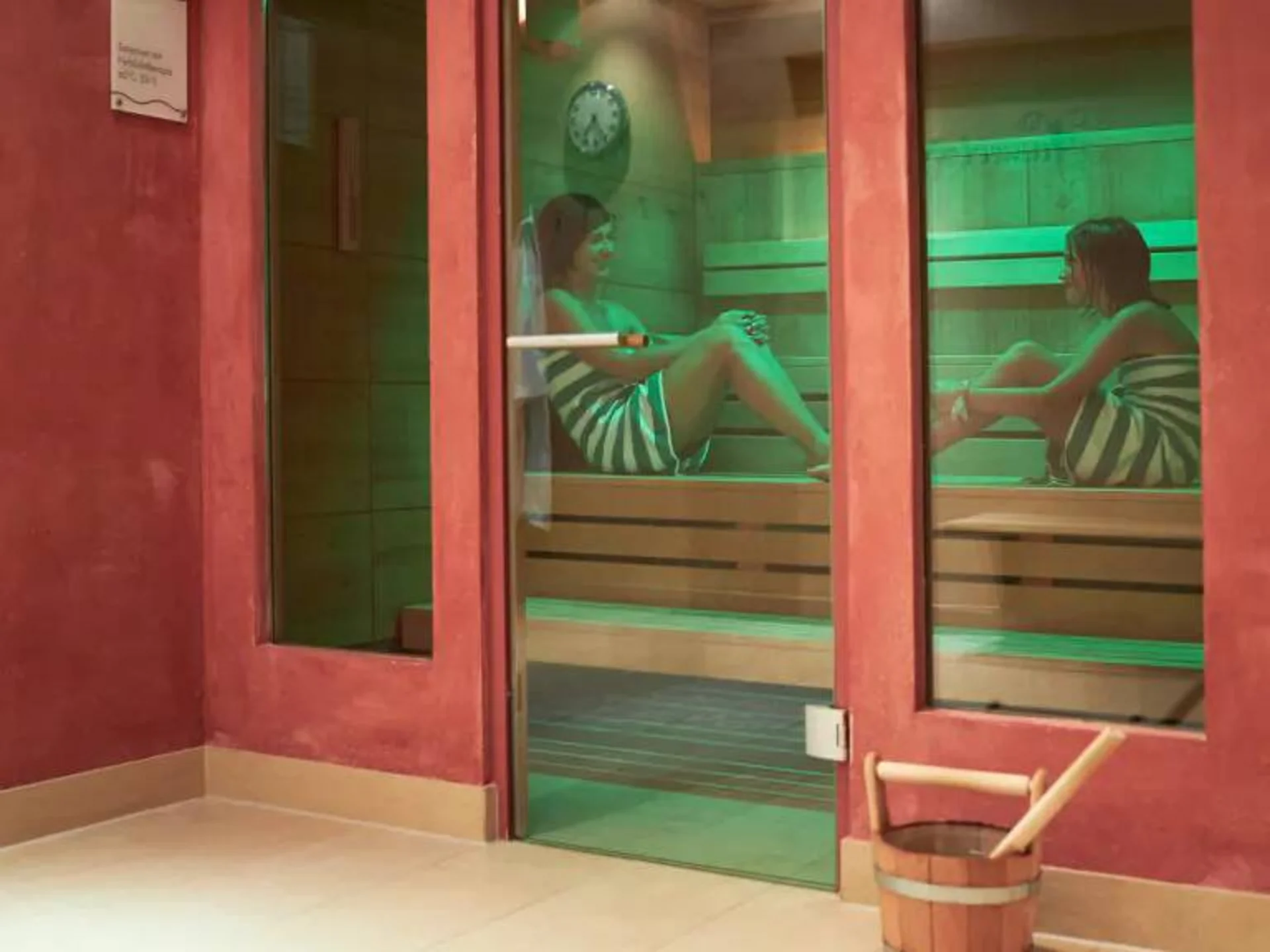 Zwei Frauen entspannen in einer Sauna mit grüner Beleuchtung