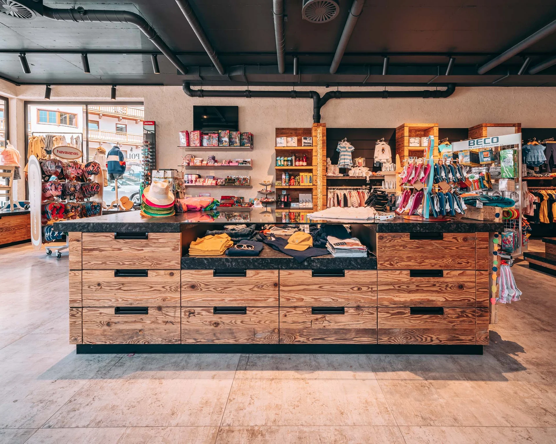 Innenansicht eines Bekleidungsgeschäfts mit Holztheke und Regalen voller Kleidung und Accessoires