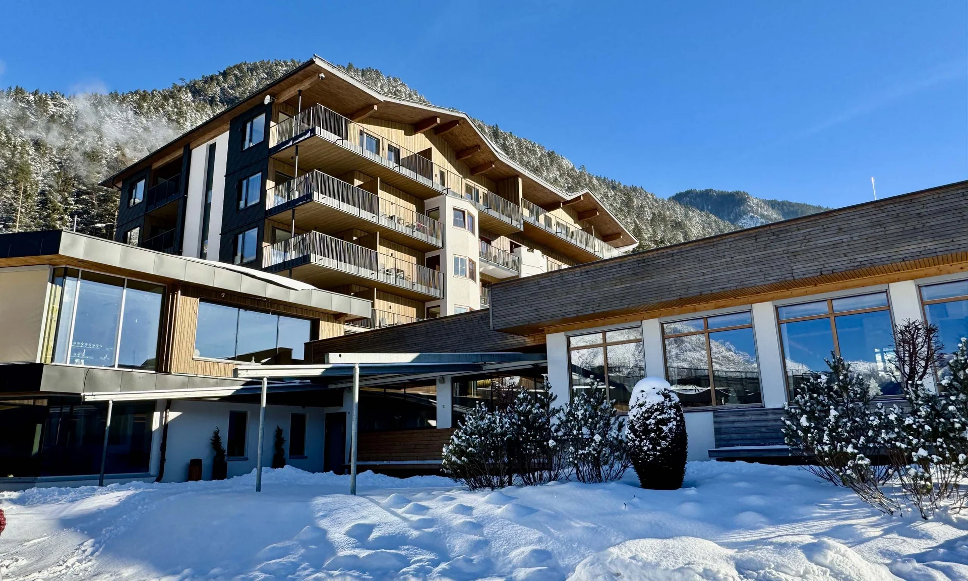 Moderne Unterkunft im Schnee mit Bergen und klarem blauem Himmel im Hintergrund