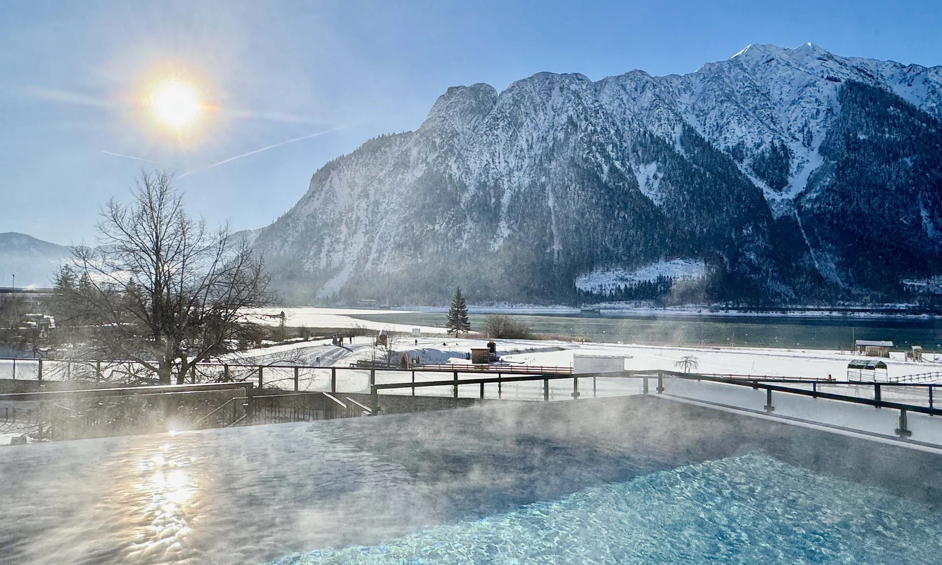 Dampfender Außenpool mit Blick auf schneebedeckte Berge und Sonne