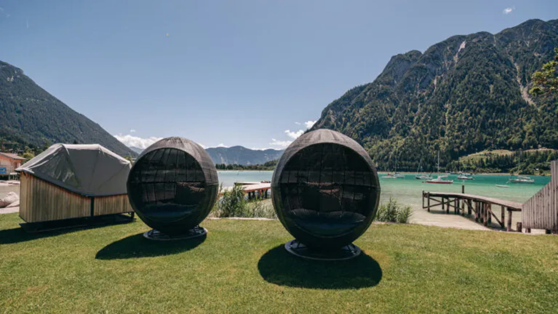 Zwei runde schwarze Gartenstühle mit Blick auf See und Berge