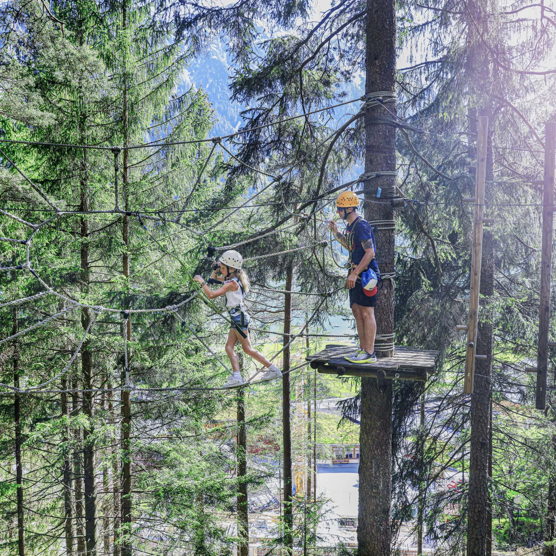 Kind und Erwachsener beim Klettern in Hochseilgarten im Wald