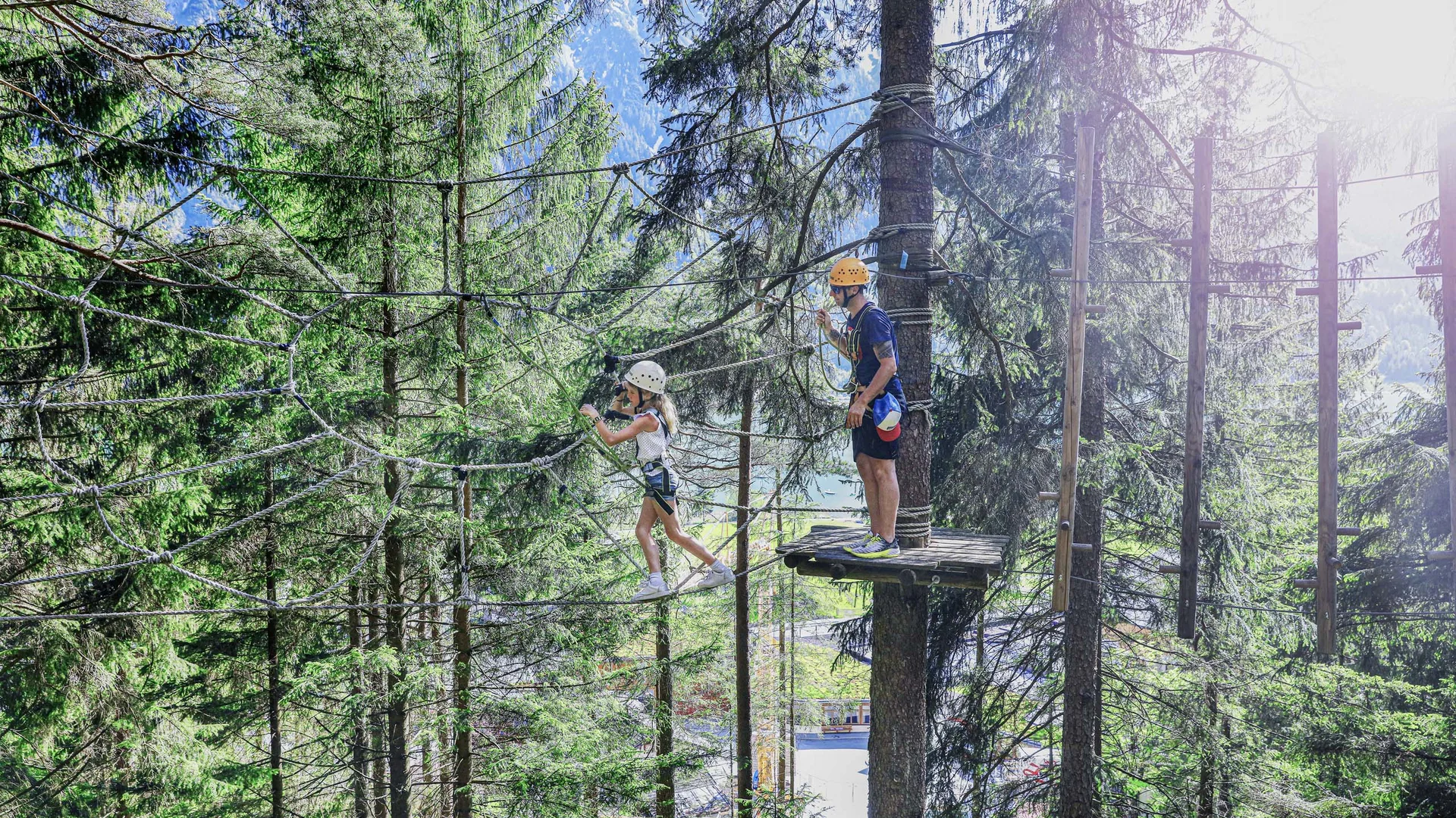 Kind und Erwachsener beim Klettern in Hochseilgarten im Wald