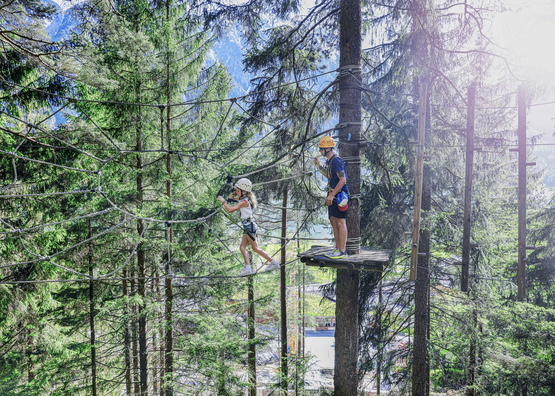Kind und Erwachsener beim Klettern in Hochseilgarten im Wald