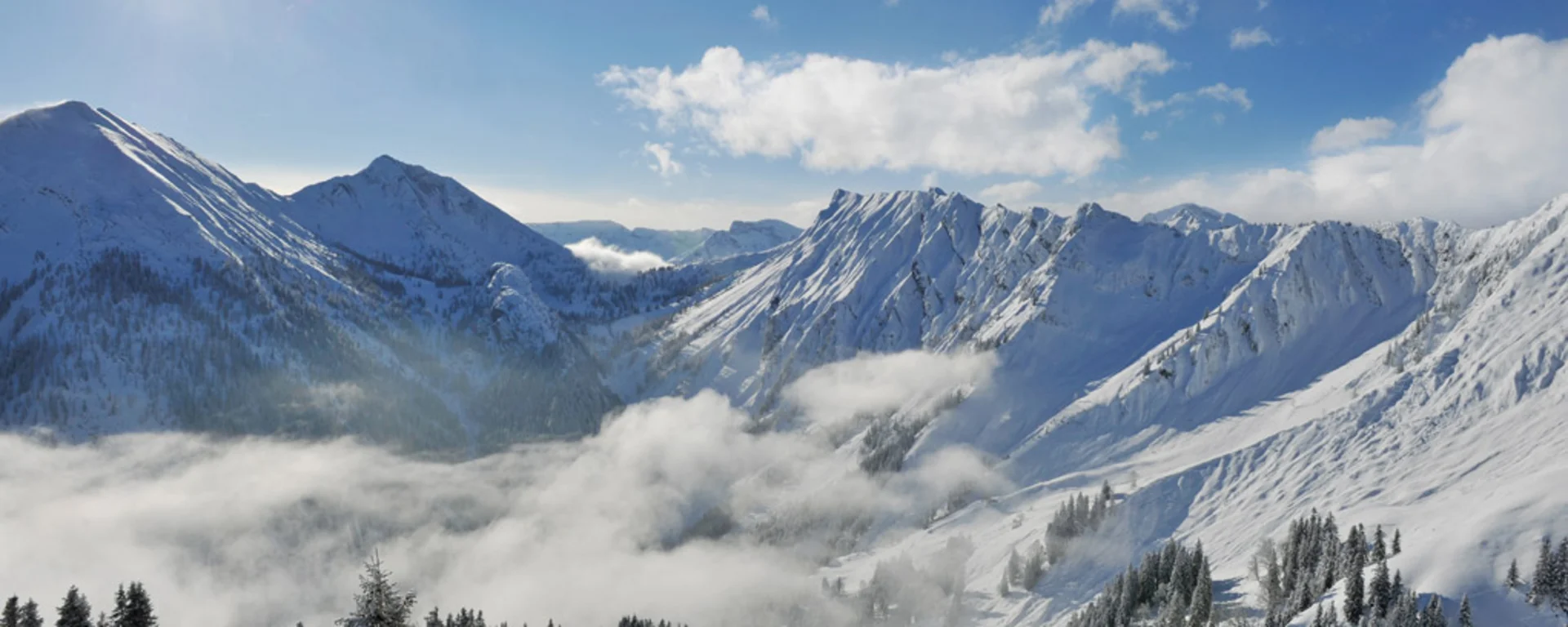 Sonnige, schneebedeckte Alpen mit Bergen, Wolken und Tannenbäumen