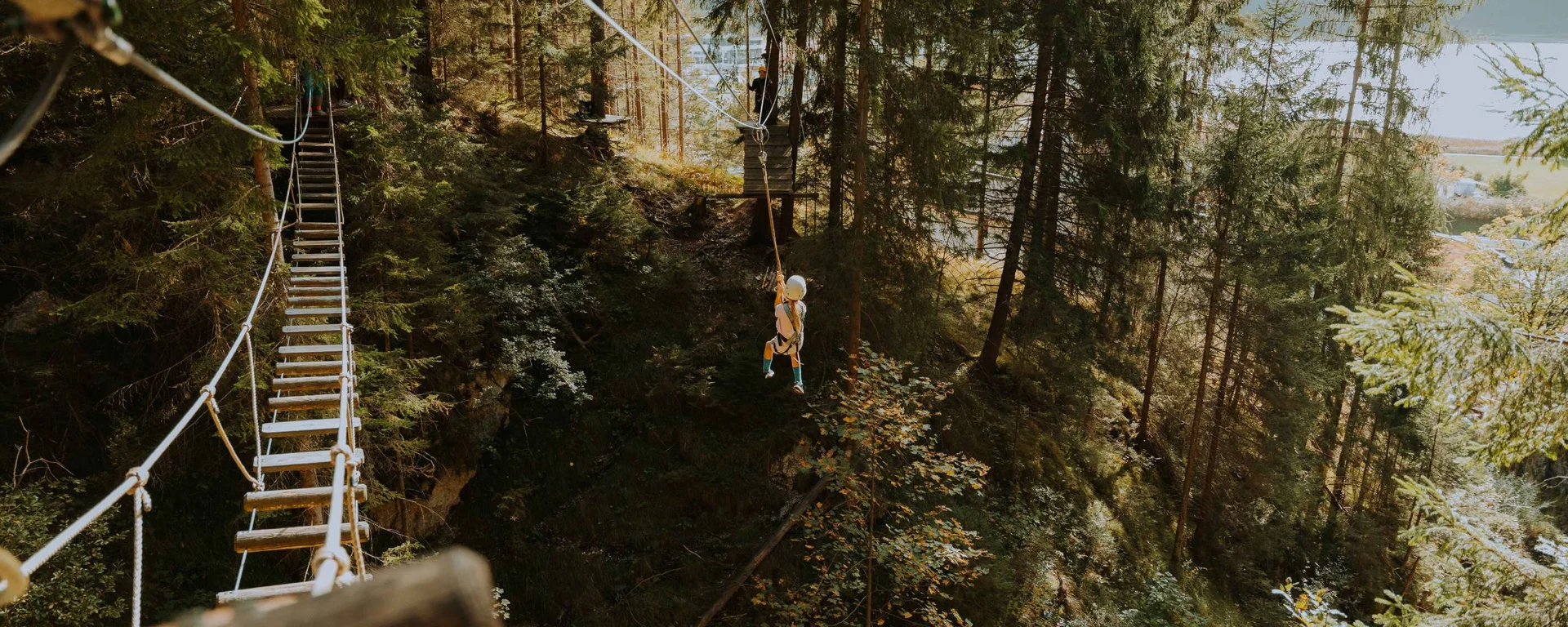 Kind fährt auf einer Seilrutsche durch einen Wald