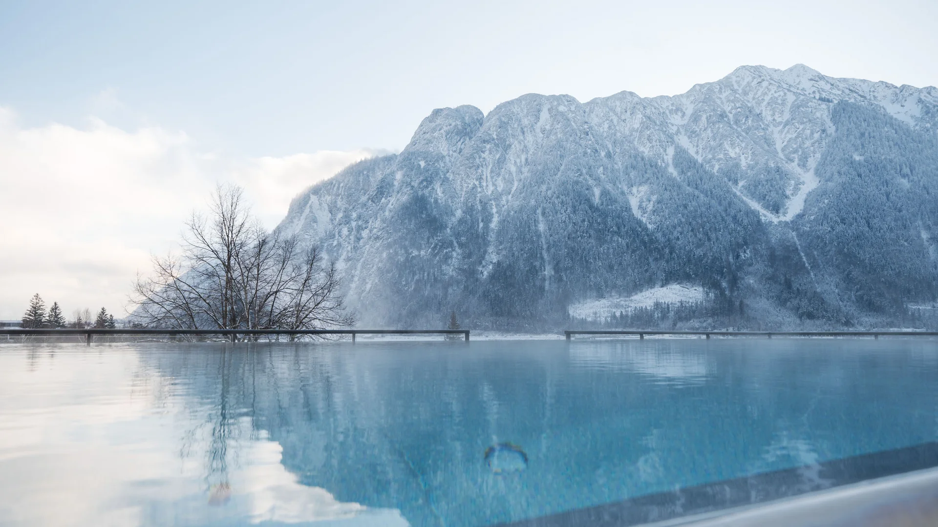 Infinity-Pool mit Blick auf schneebedeckte Berge und Nebel im Winter