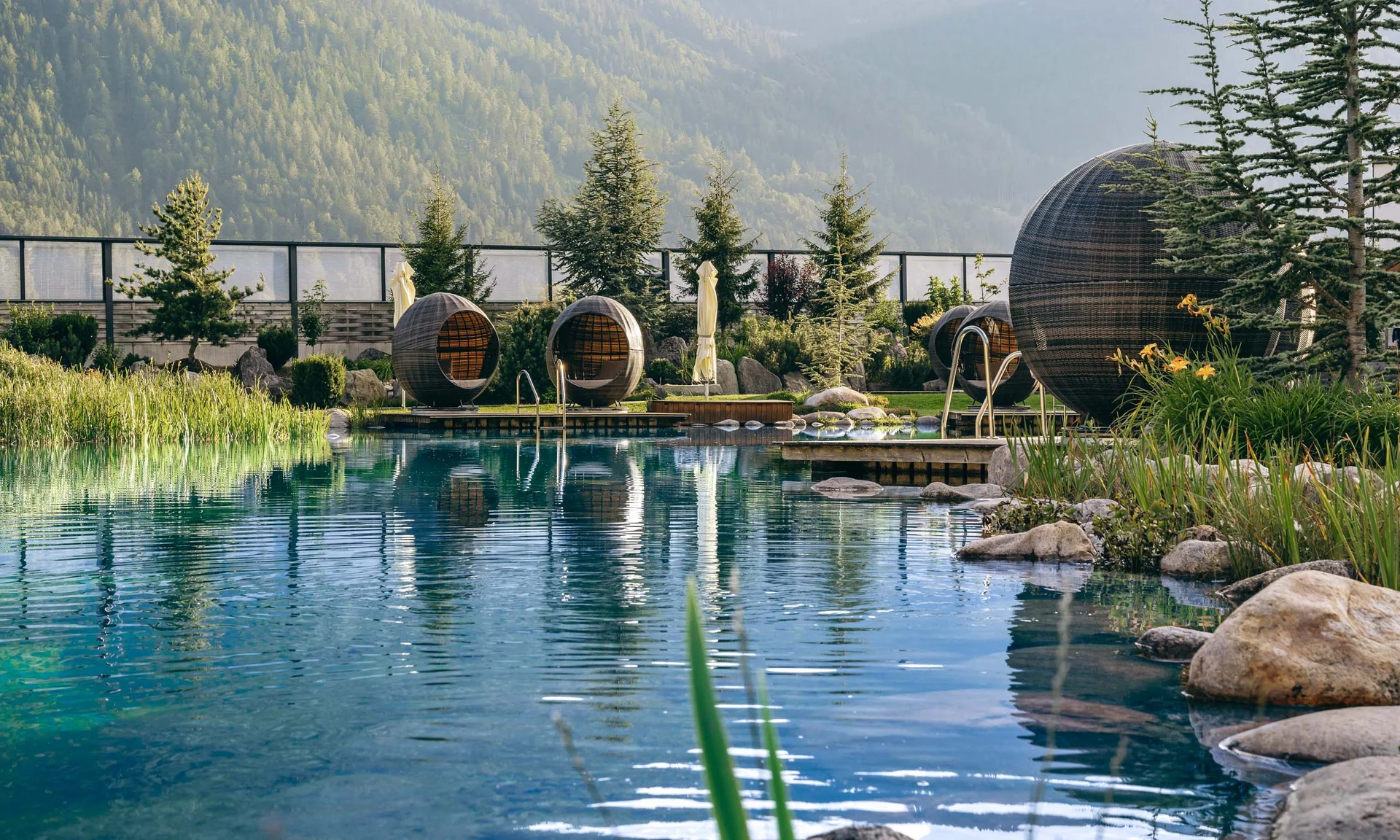 Natural pool with round egg-shaped lounges and mountains in the background