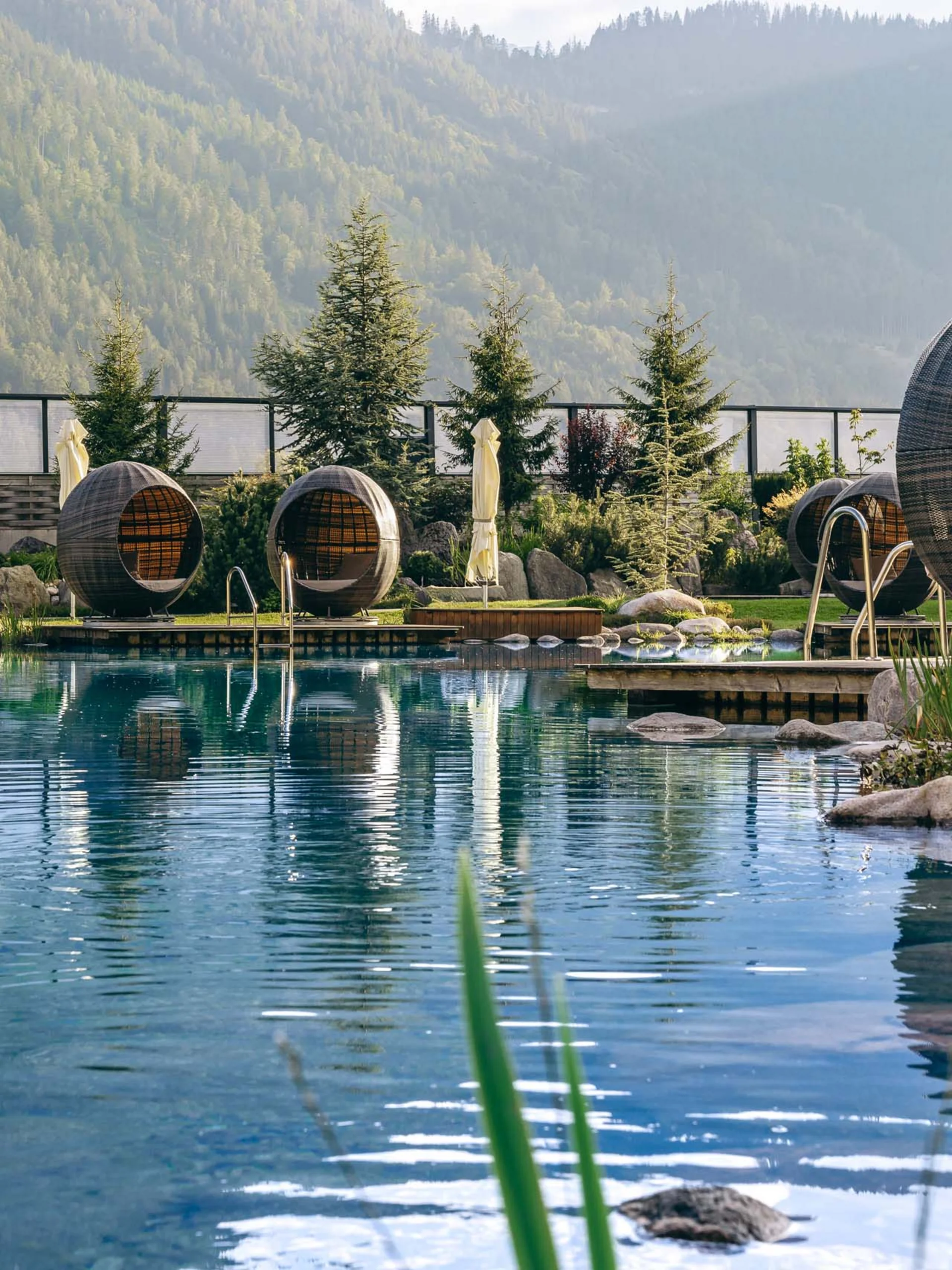 Natürlicher Pool mit runden Lounge-Eiern und Bergen im Hintergrund