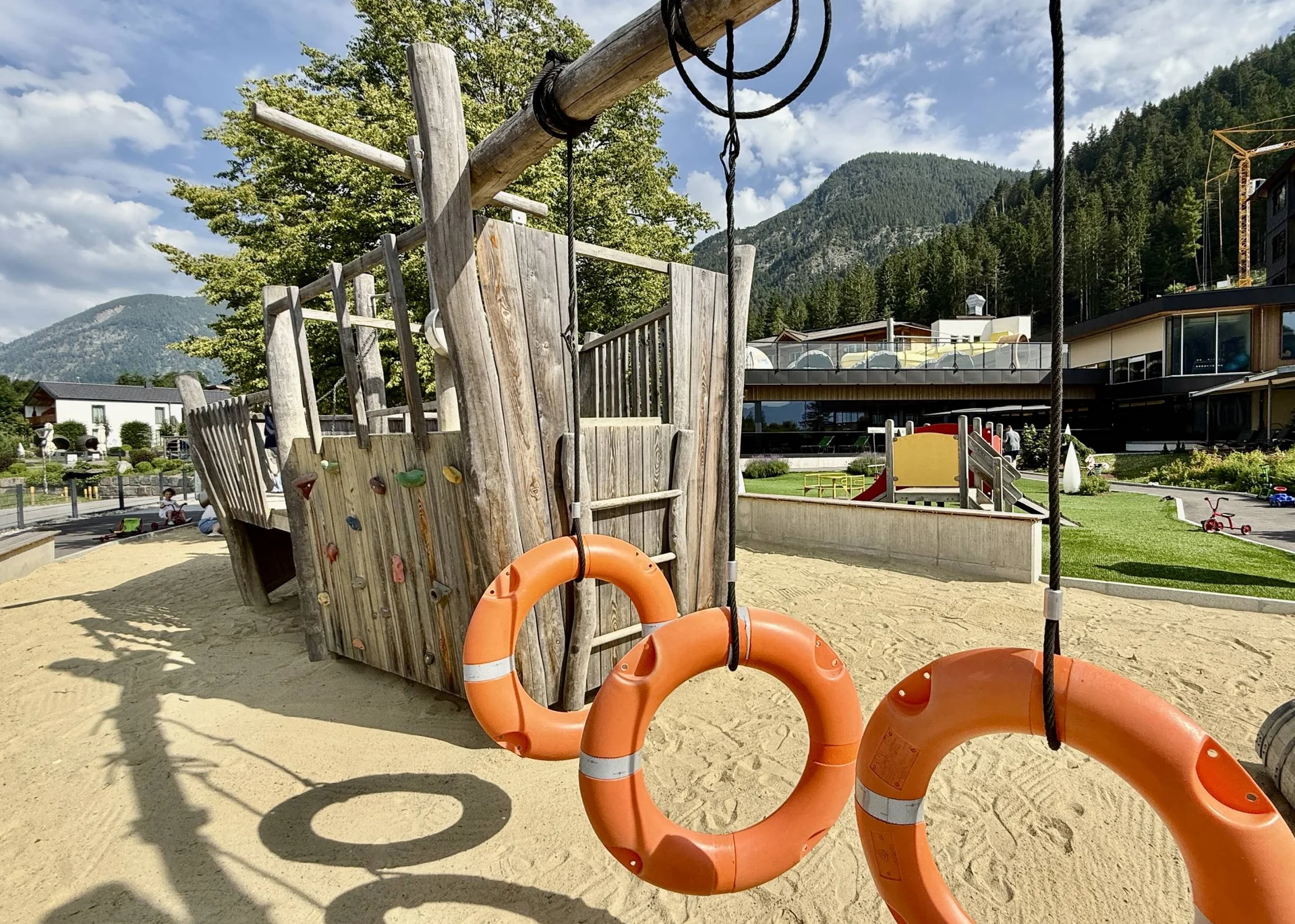 Spielplatz mit hölzernem Piratenschiff und drei orangenen Rettungsringen im Sand