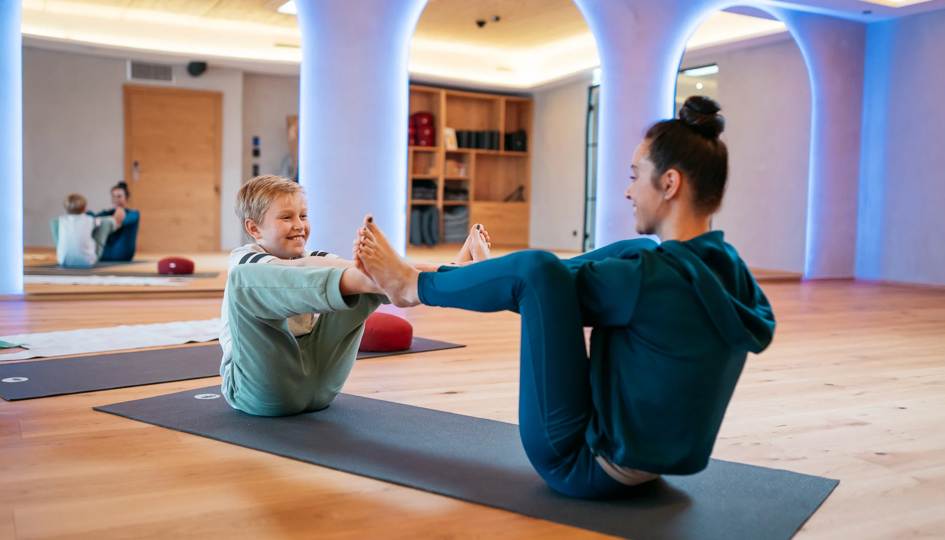 Frau und Kind machen gemeinsam Yogaübungen auf Matten in einem Raum